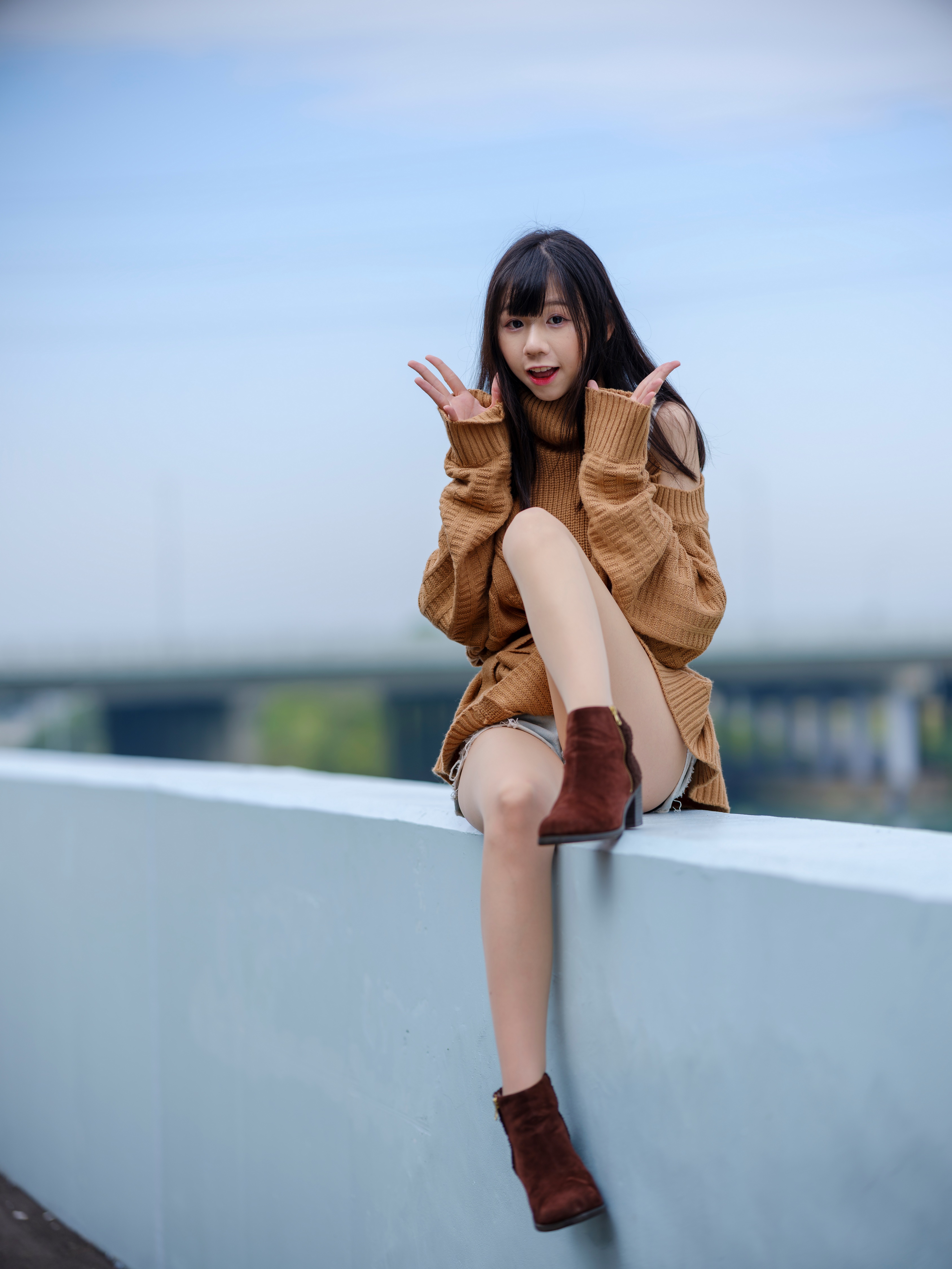 Brunette girl in sweater sitting outdoors HD Phone Wallpaper
