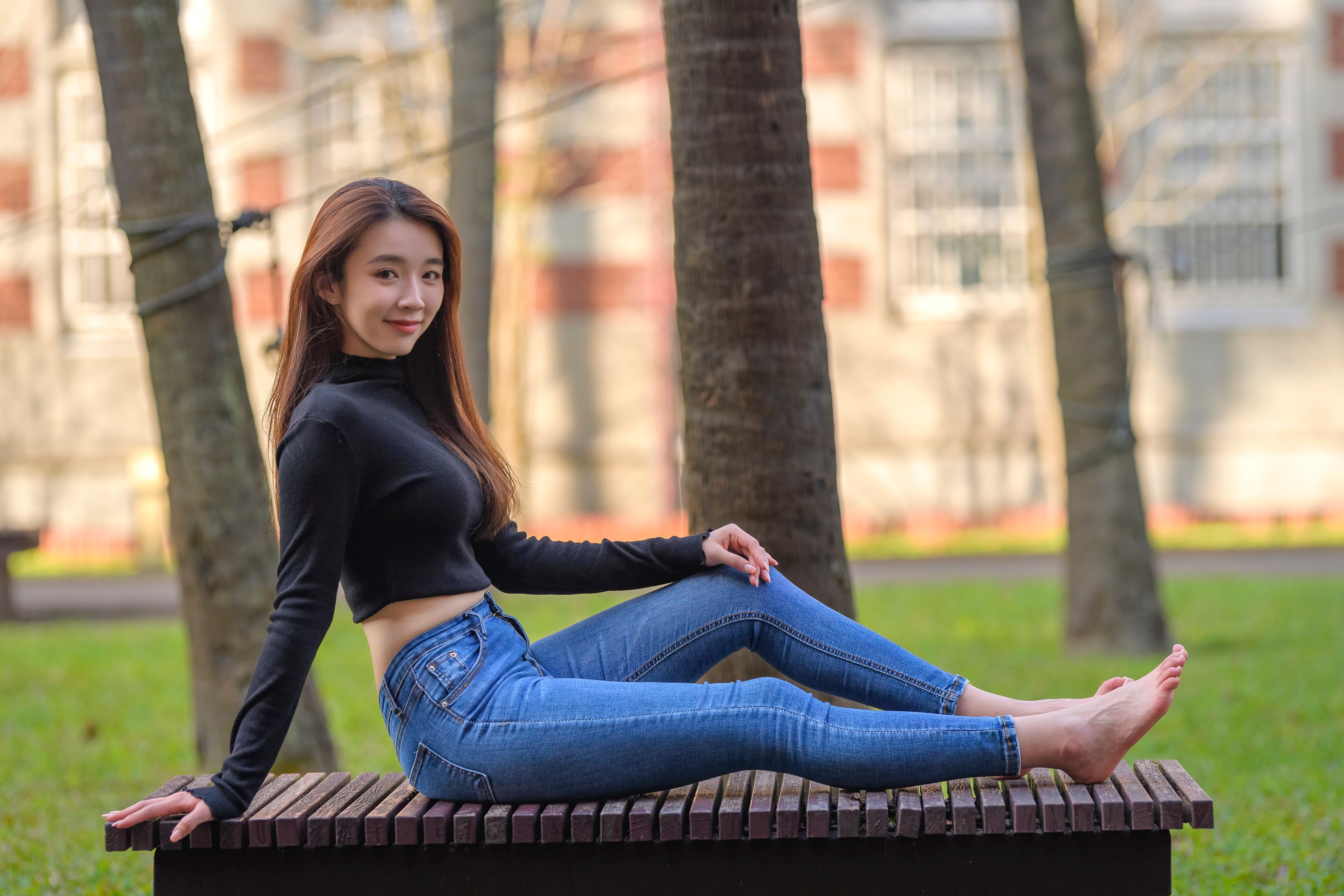 Asian woman in jeans sitting on a bench HD Wallpaper