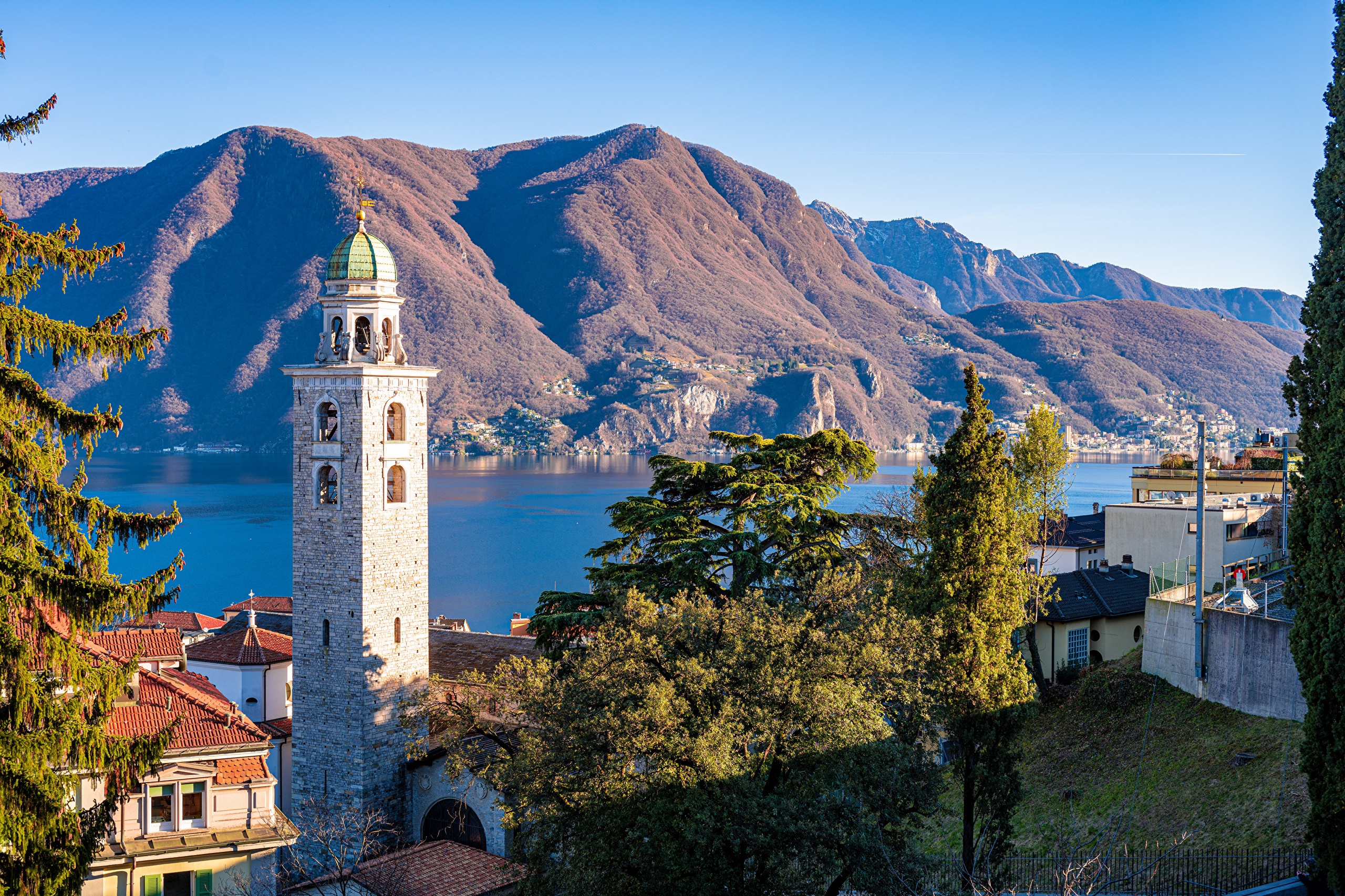 Bell tower by Lake Lugano with mountains in Switzerland HD Wallpaper