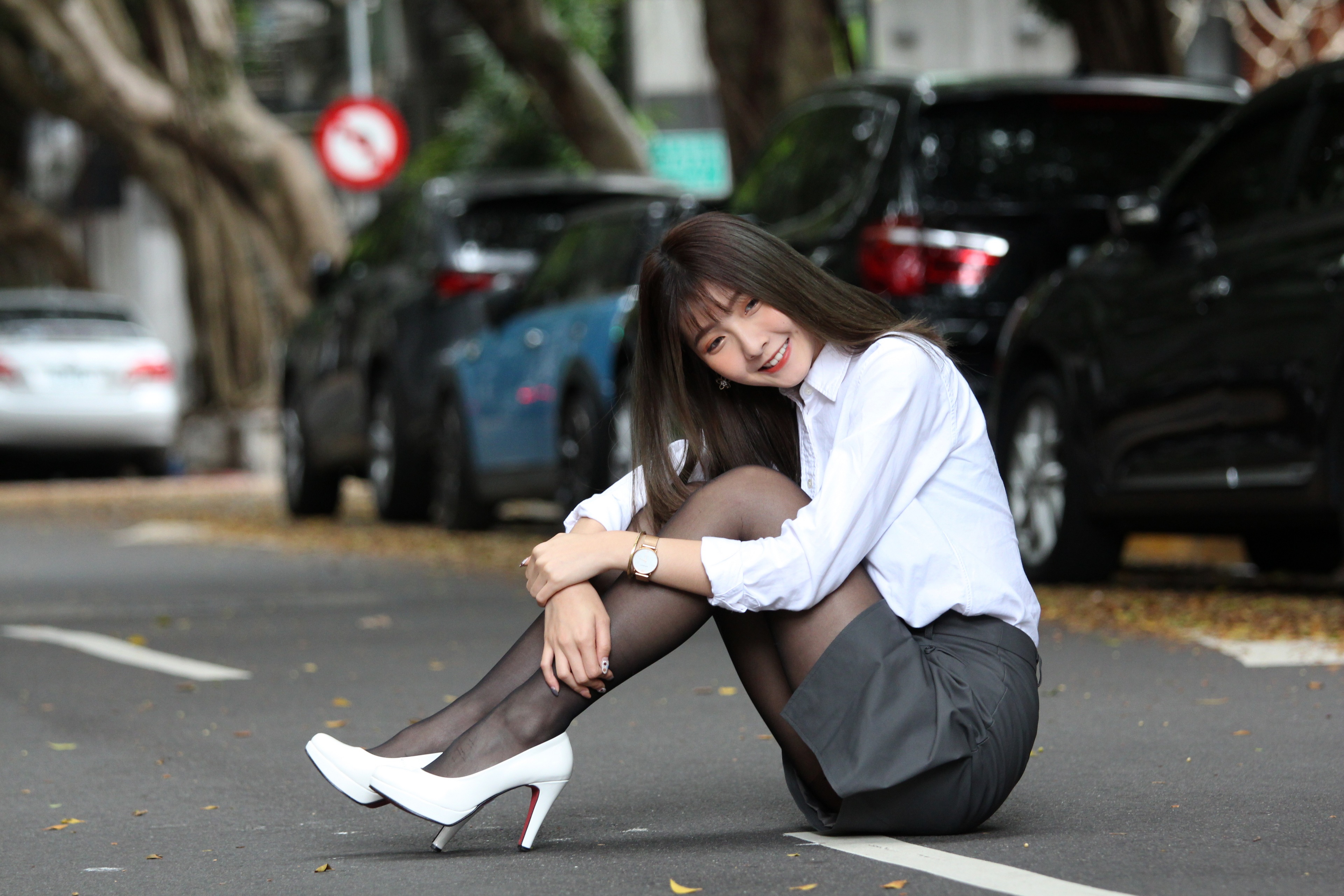 Asian woman in skirt and blouse sitting on street HD Wallpaper