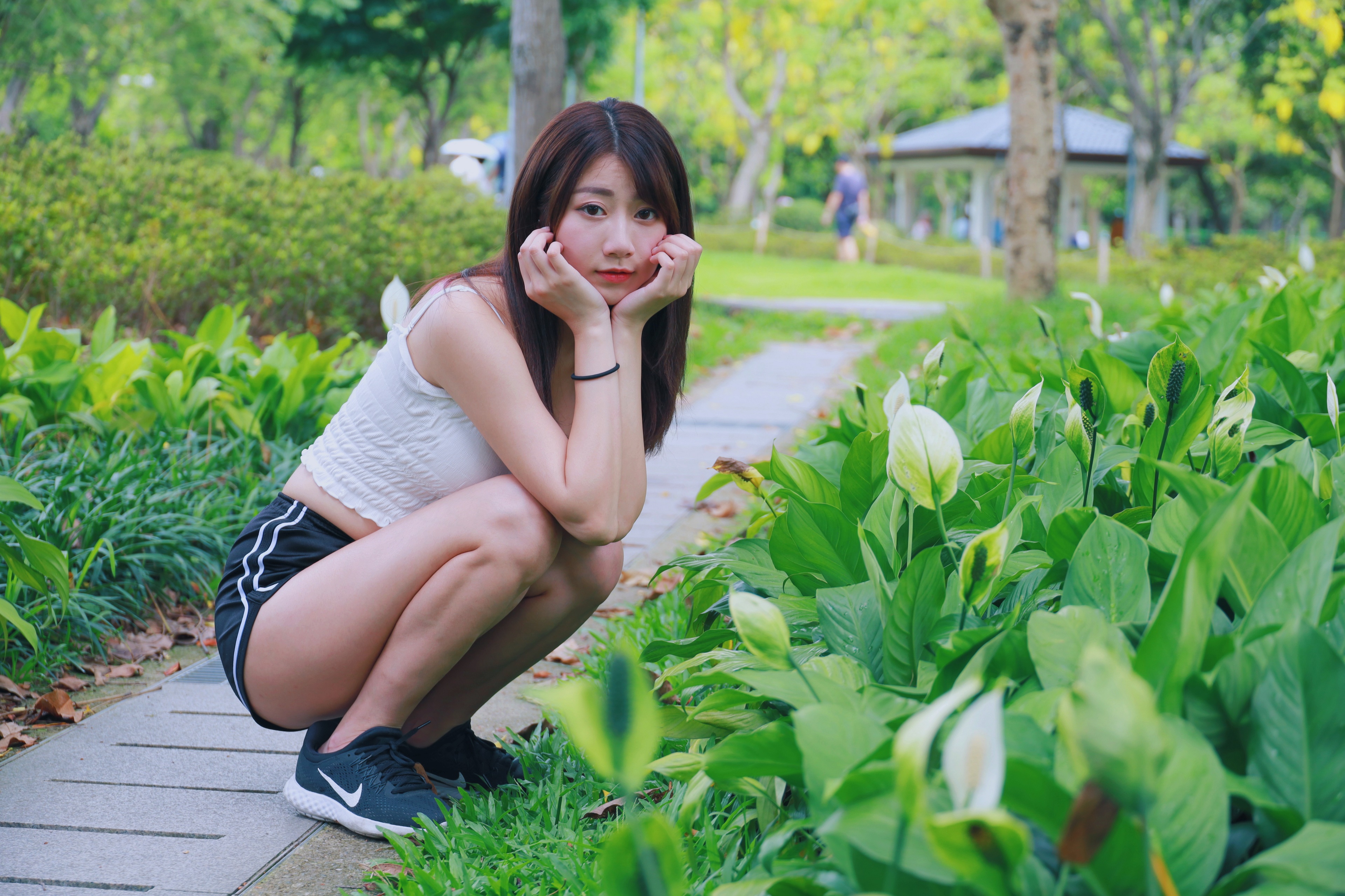 Asian woman squatting in a park HD Wallpaper