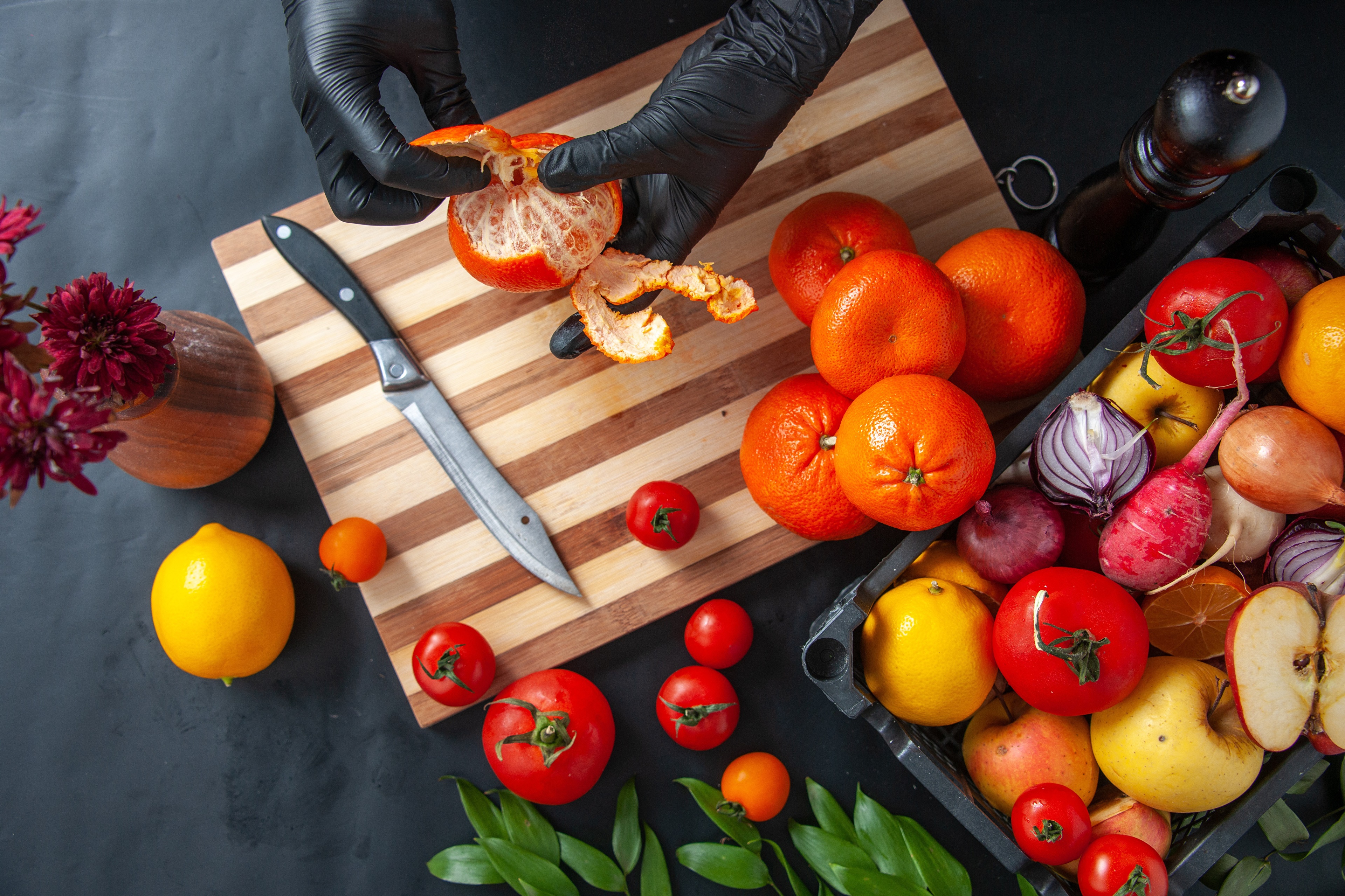 Hands peeling a tangerine on a cutting board with fruits and vegetables HD Wallpaper