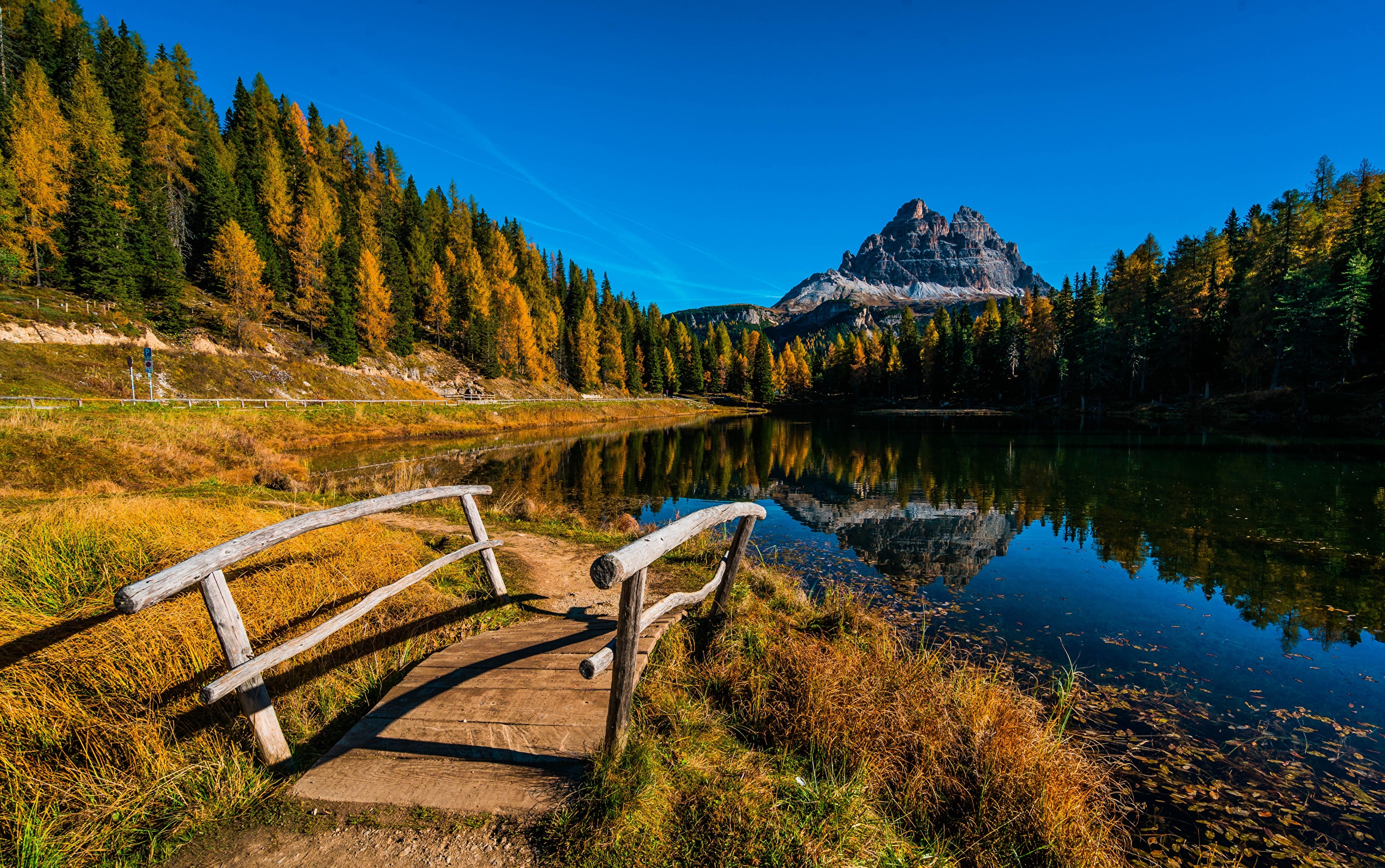 Wooden bridge over a lake with autumn trees and mountains HD Wallpaper