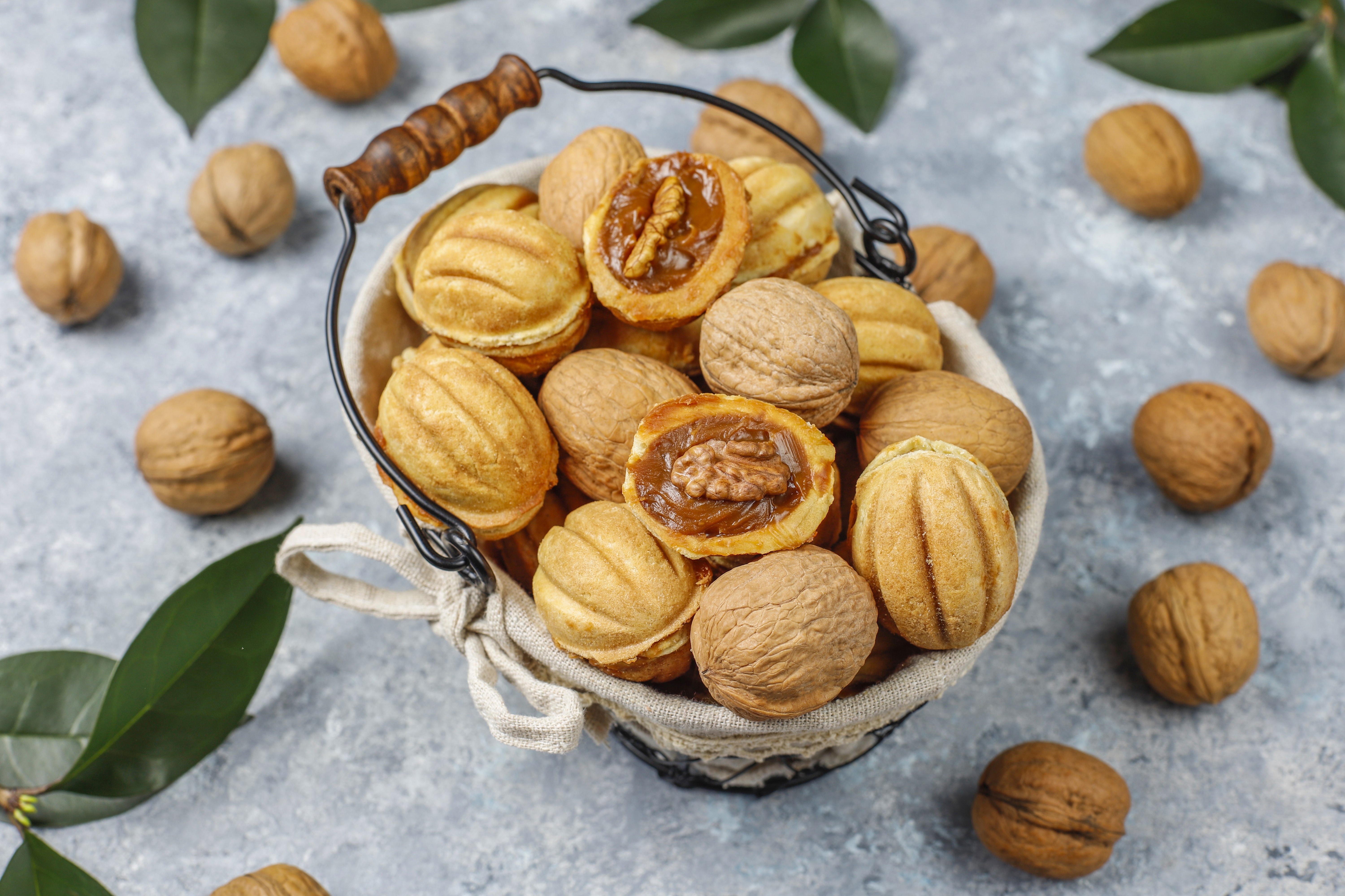 Walnut pastries in a wicker basket with walnuts and leaves HD Wallpaper