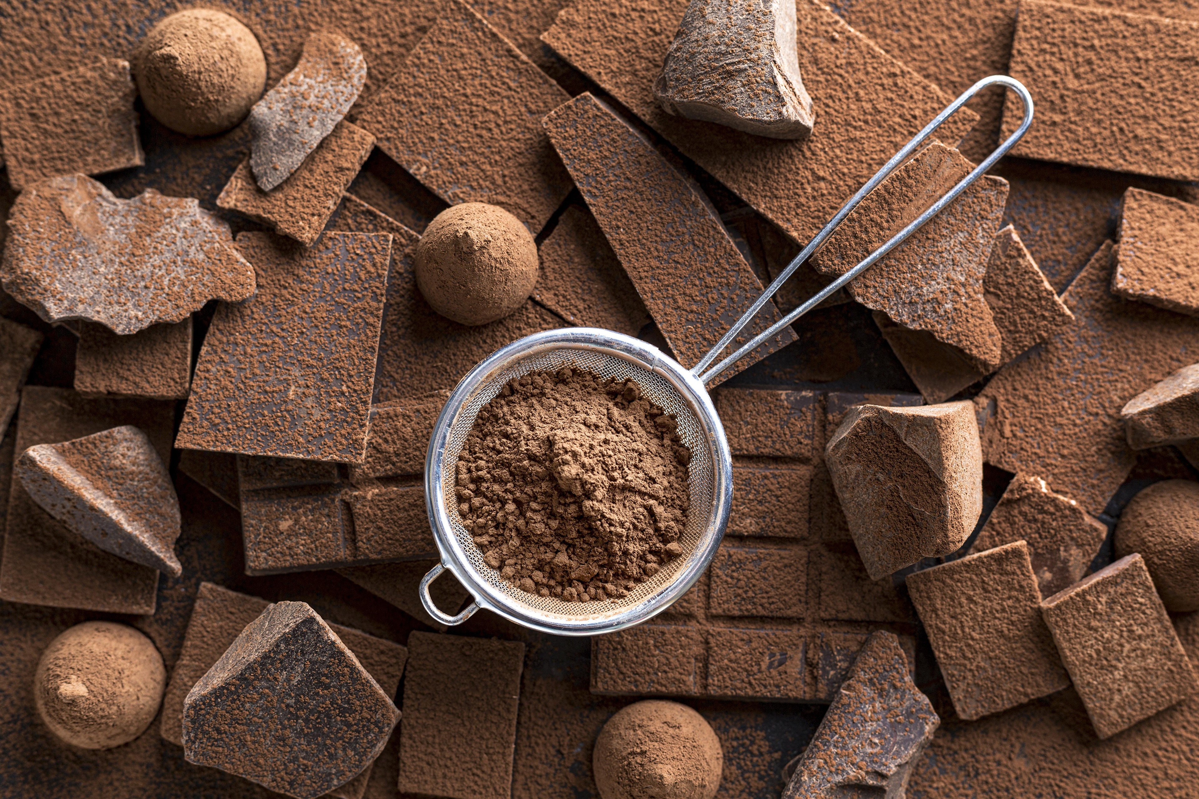 Chocolate pieces and cocoa powder in a tea strainer HD Wallpaper