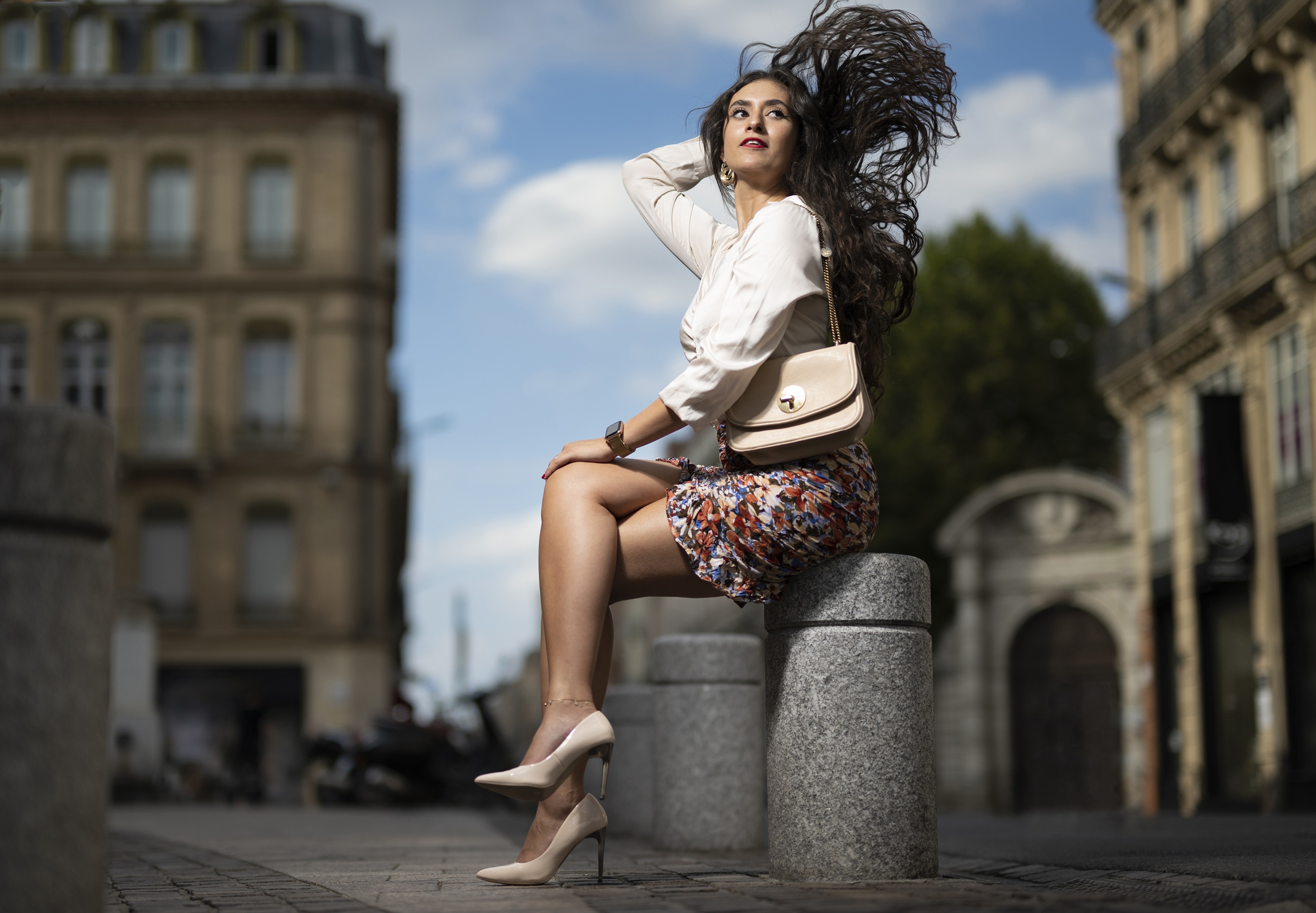 Brunette girl sitting on a stone bollard in the wind HD Wallpaper