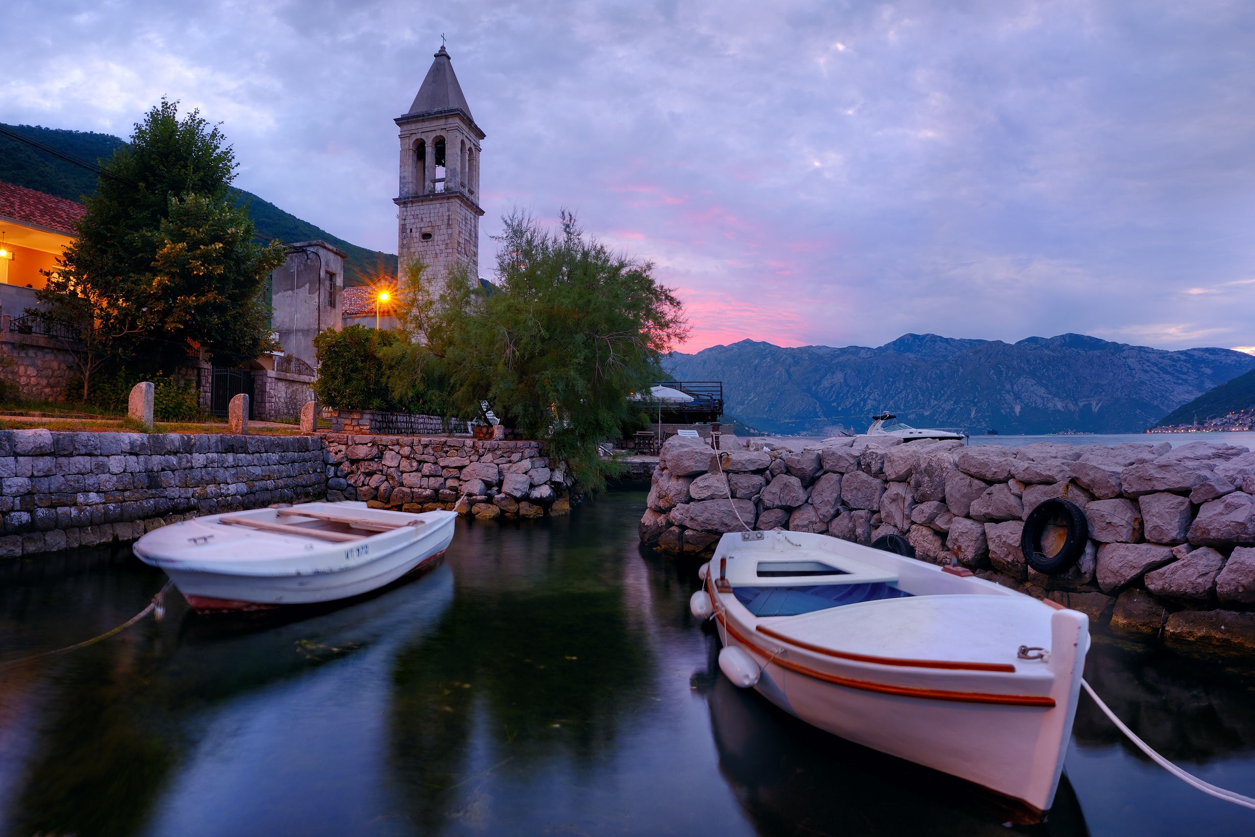 Boats by a waterfront tower in Stoliv, Montenegro at dusk HD Wallpaper