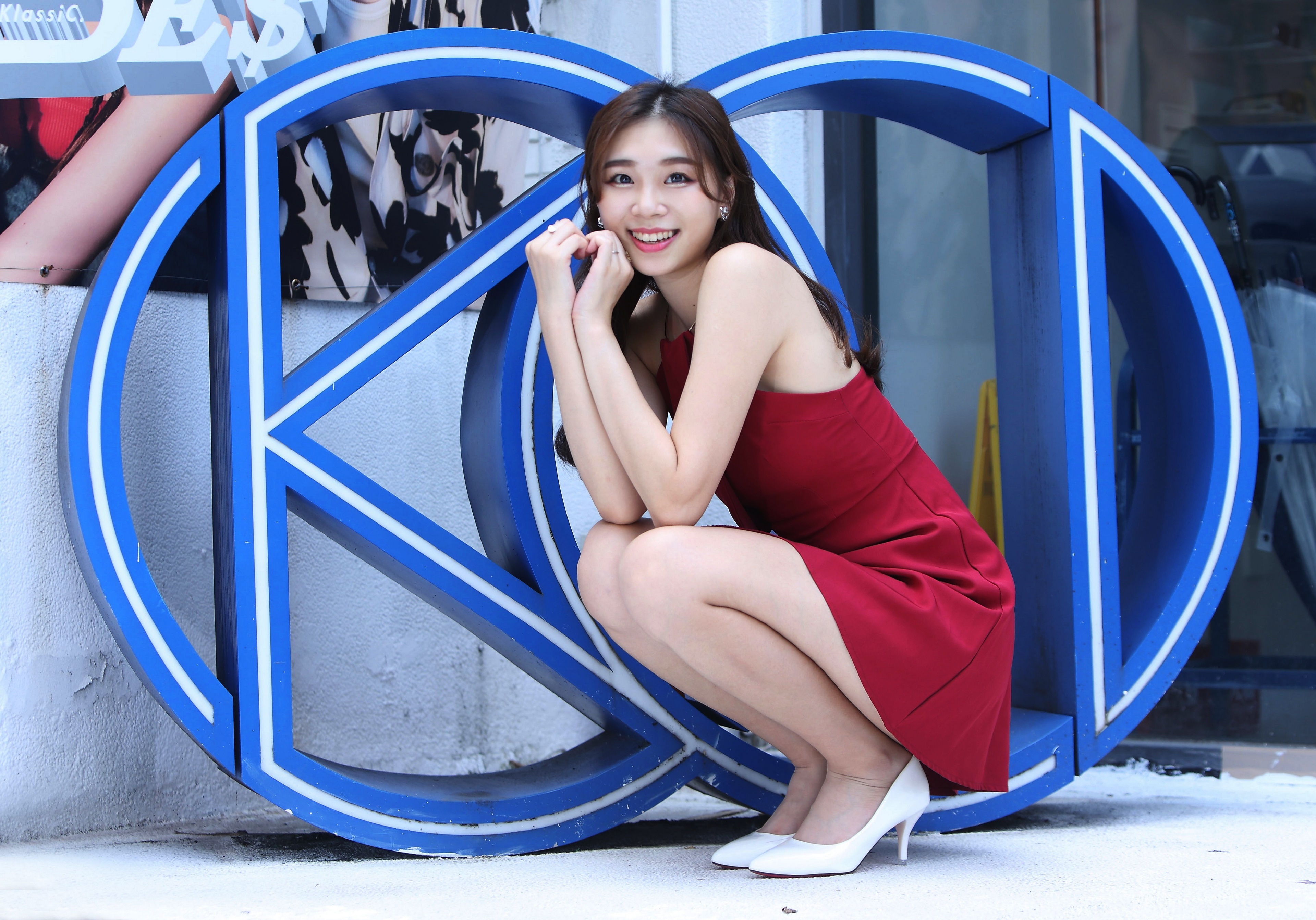 Asian woman in red dress posing near blue letters HD Wallpaper