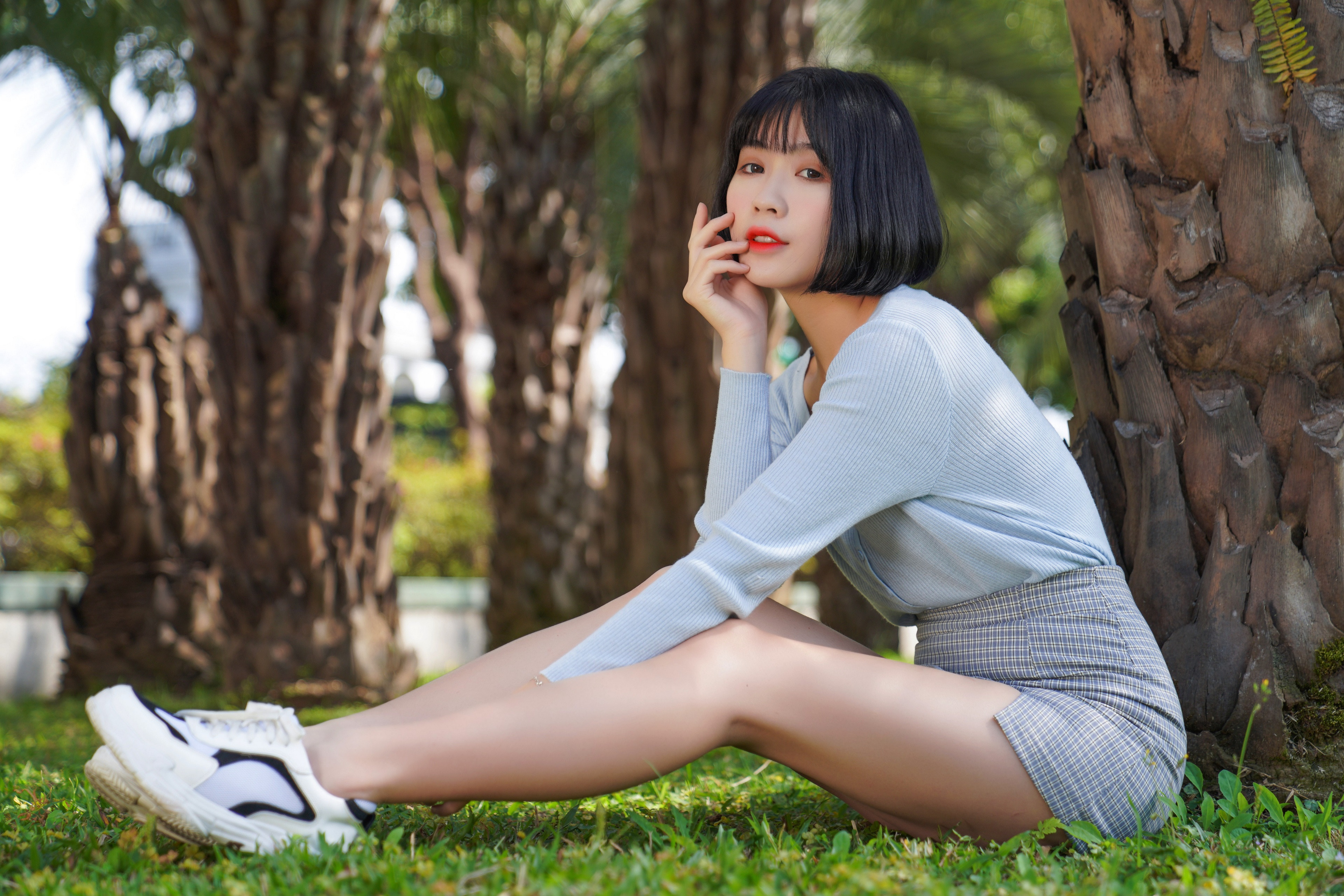 Asian girl sitting on grass near palm trees HD Wallpaper