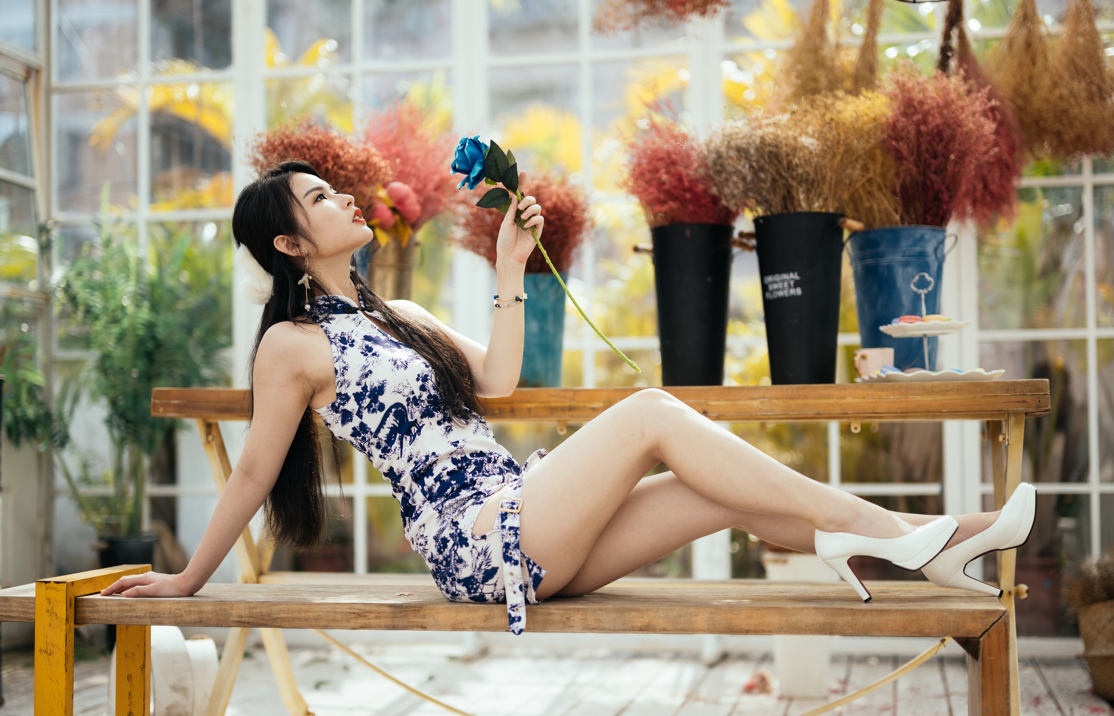 Asian woman in dress posing with flower on bench HD Wallpaper