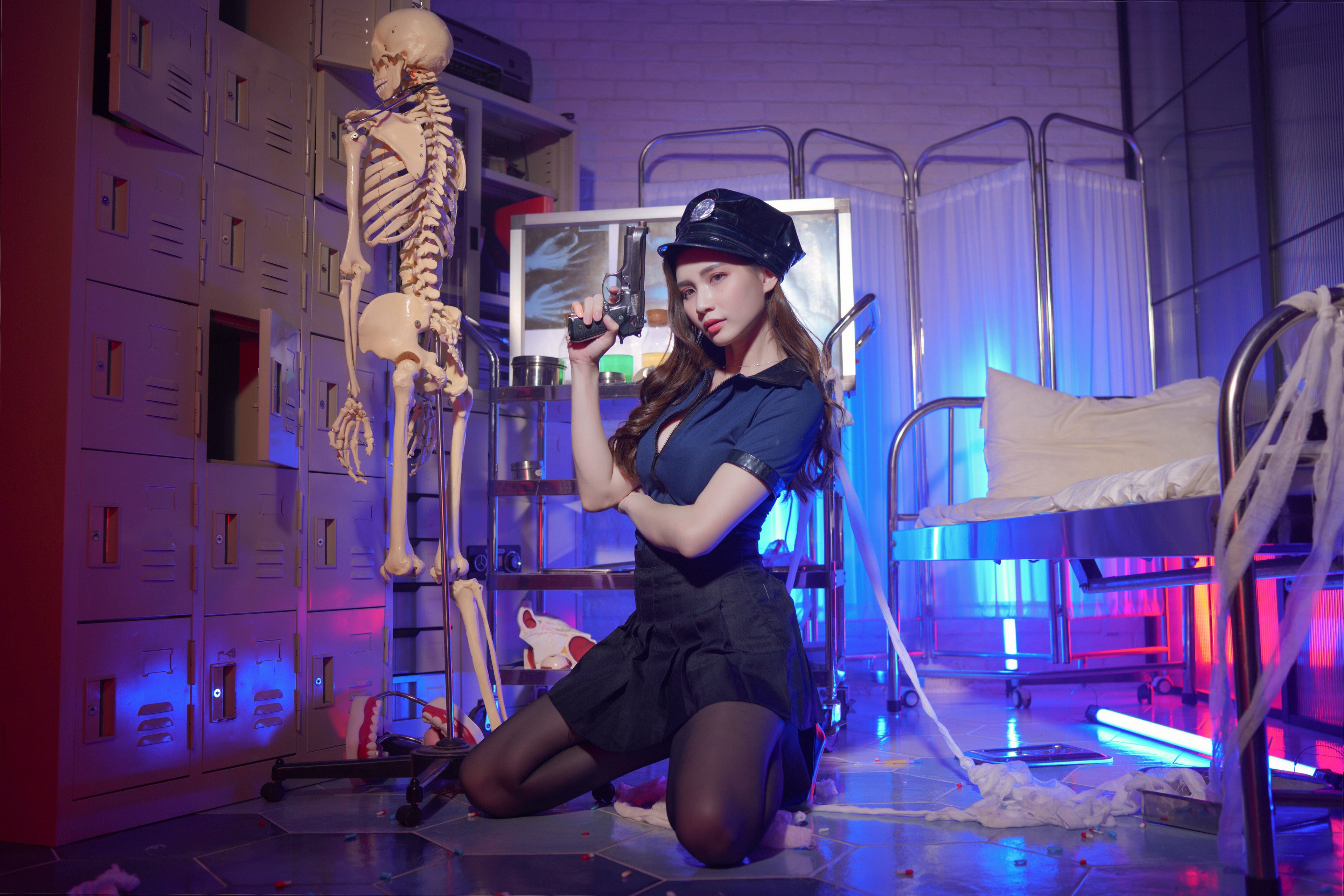 Woman in police uniform holding a pistol near a skeleton HD Wallpaper