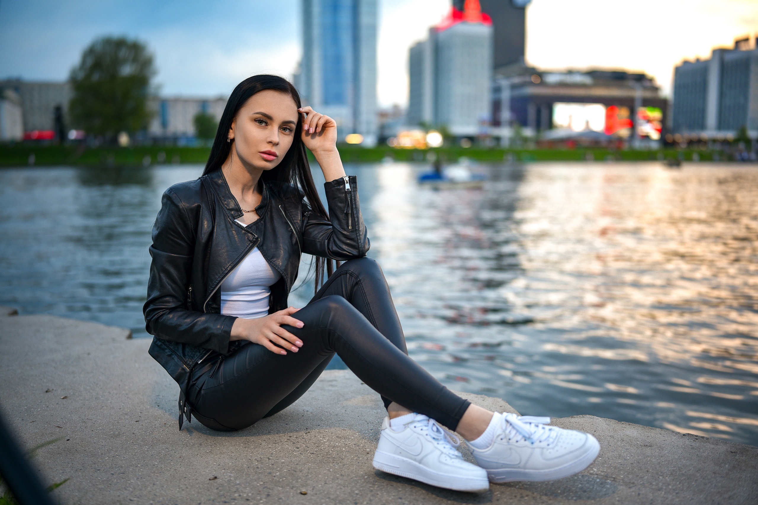 Brunette girl in leather jacket sitting by water HD Wallpaper