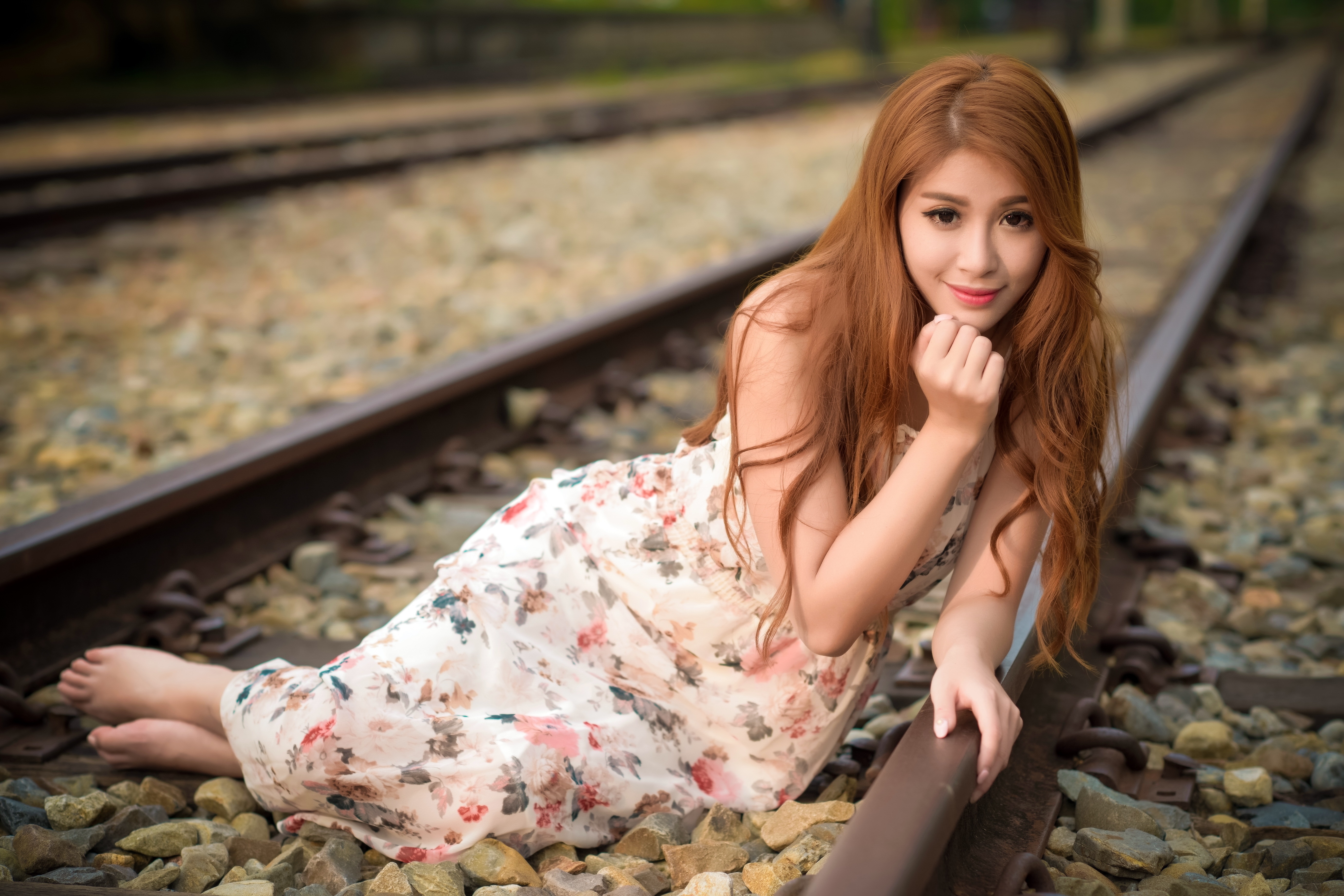 Asian woman with brown hair lying on train tracks HD Wallpaper