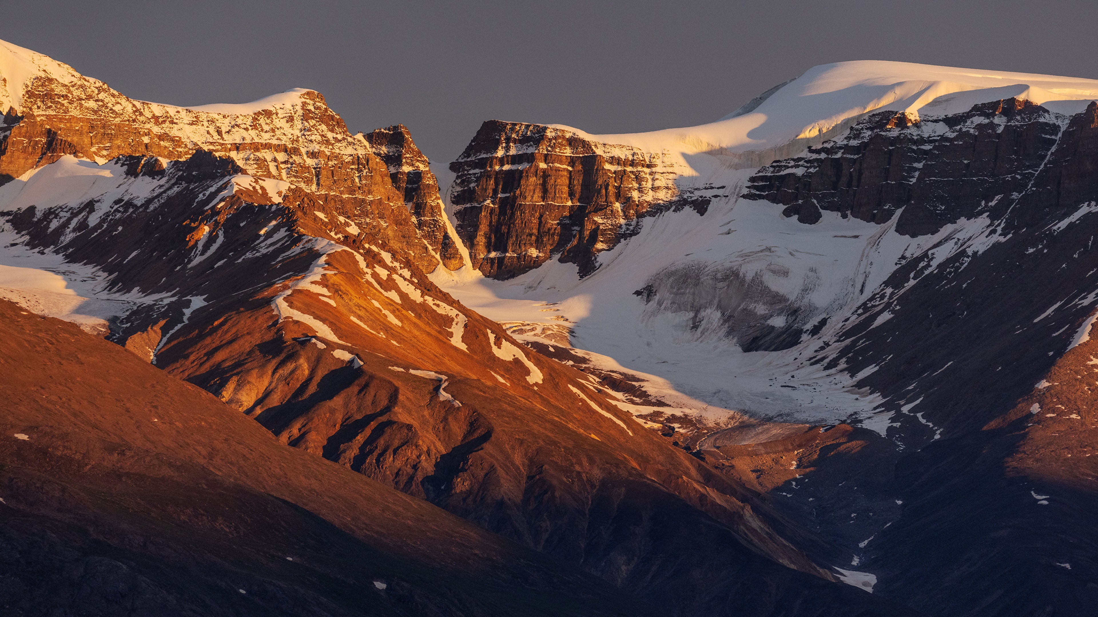 Mountains with snow and golden light HD Wallpaper