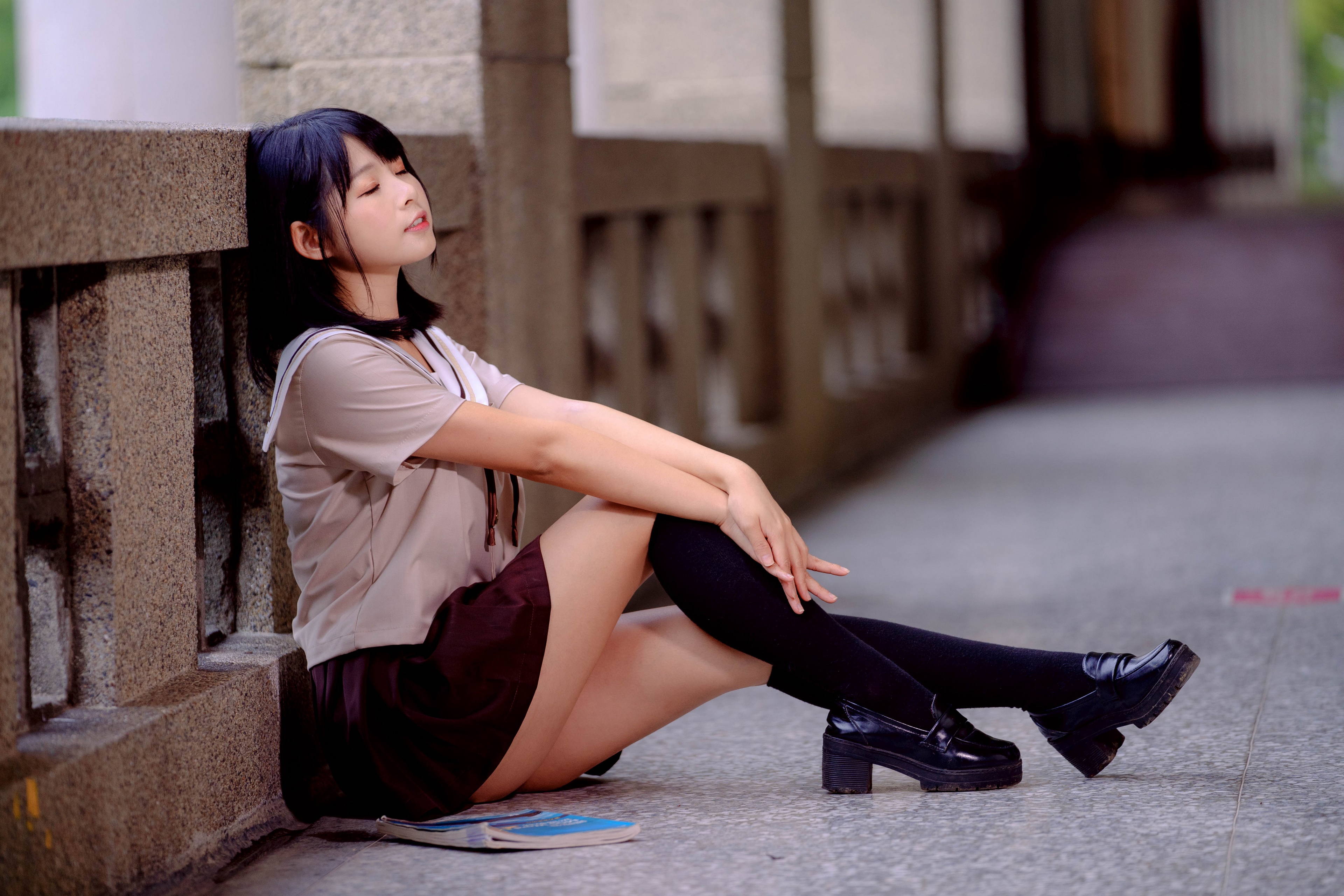 Asian girl in school uniform sitting by a wall HD Wallpaper