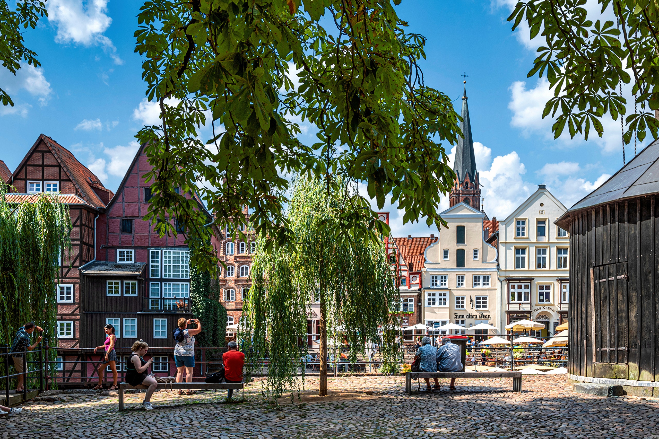 People sitting on benches in front of historic buildings in Germany HD Wallpaper