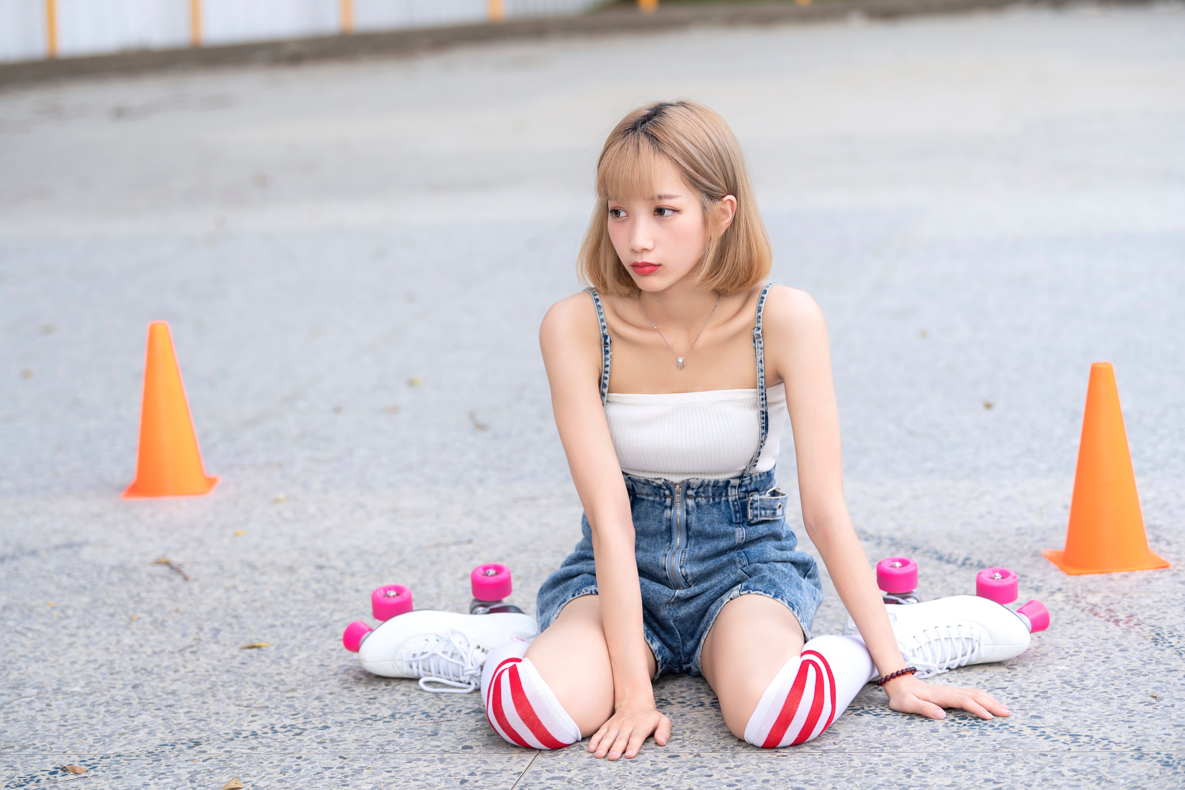 Asian girl in roller skates and shorts sitting on ground HD Wallpaper