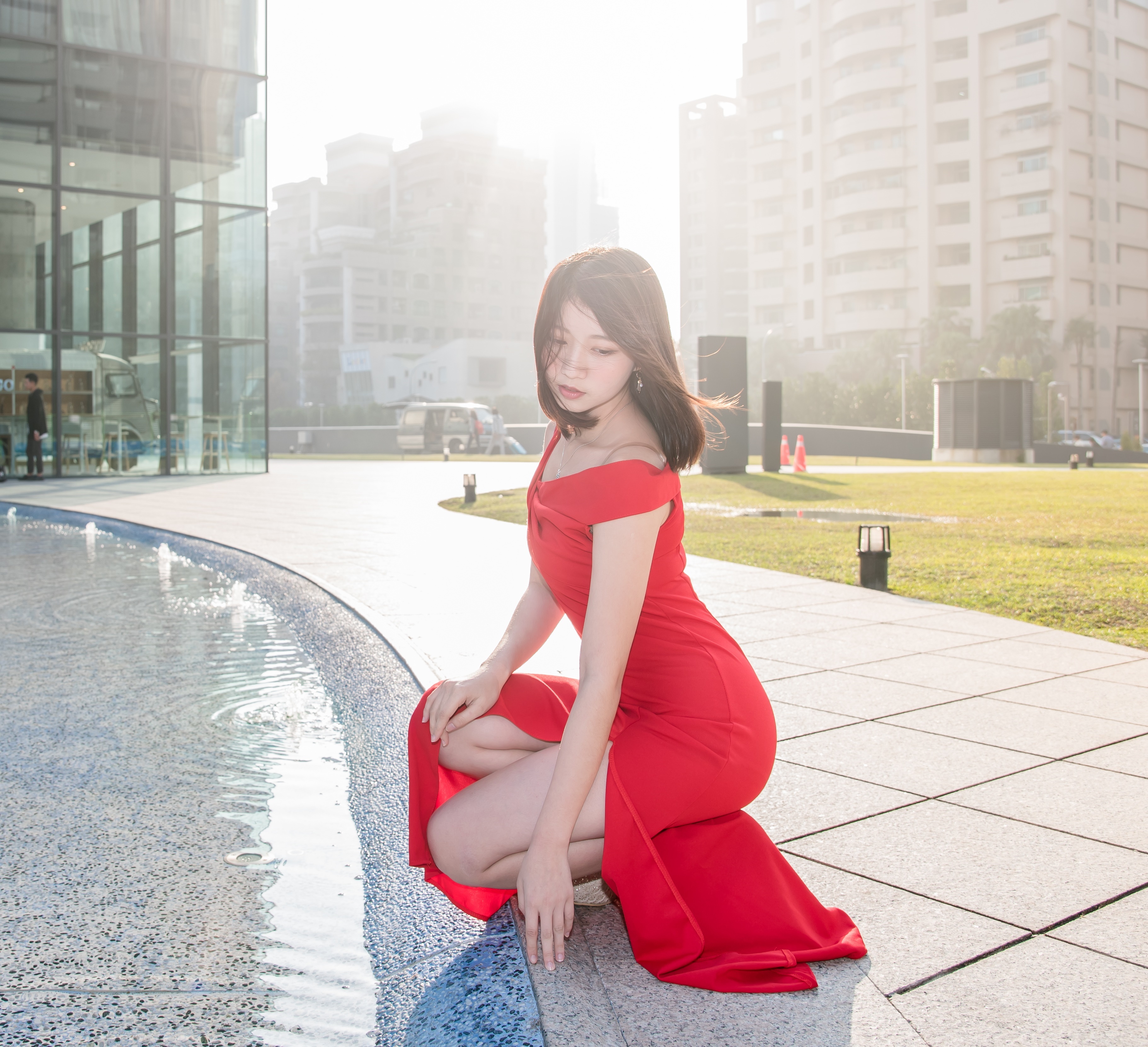 Asian woman in red dress posing by a fountain HD Wallpaper