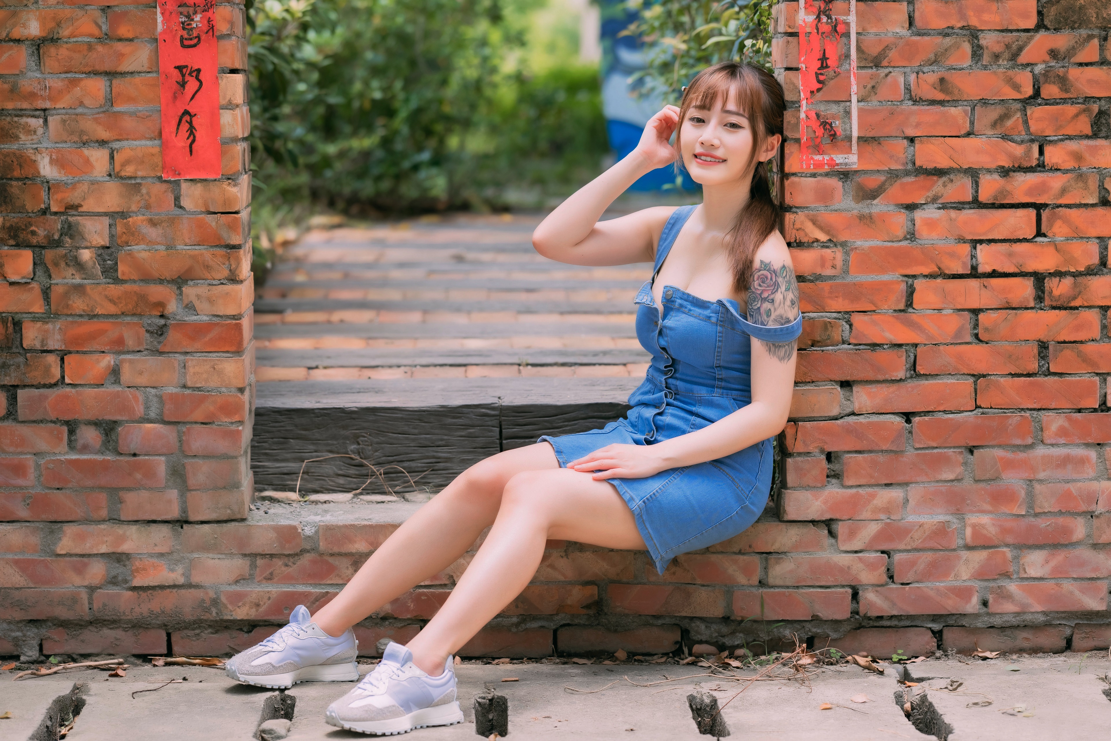 Asian woman sitting by a brick wall HD Wallpaper