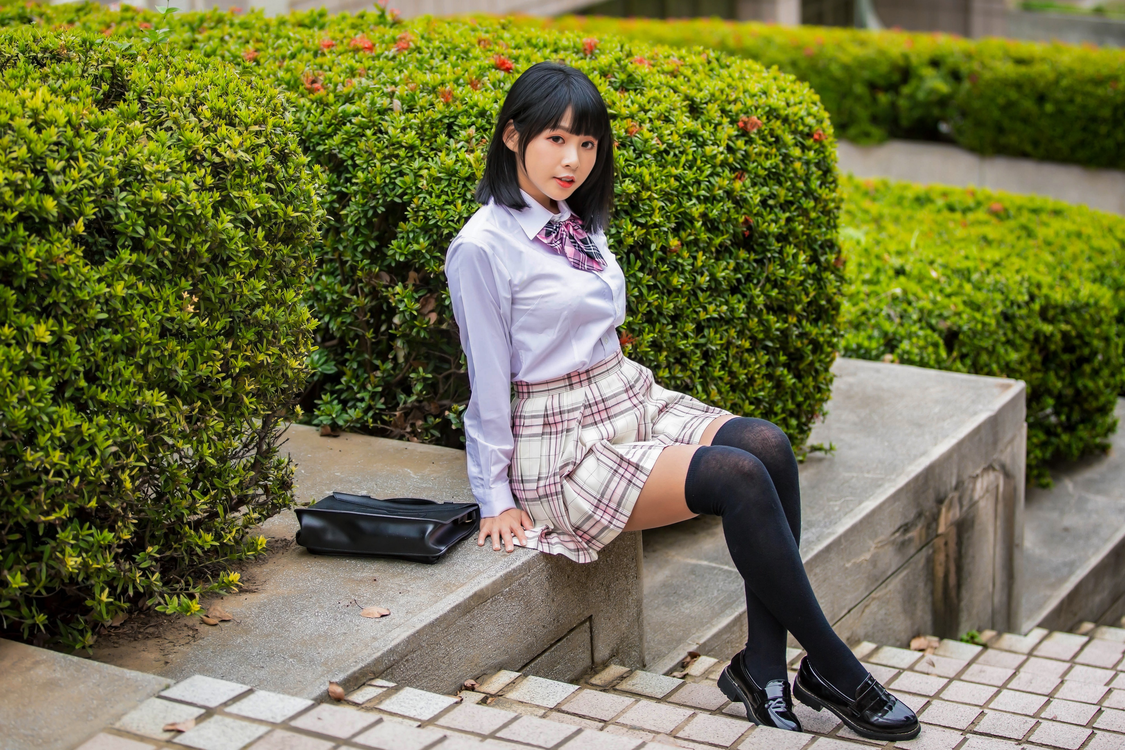 Asian girl in school uniform sitting by bushes HD Wallpaper