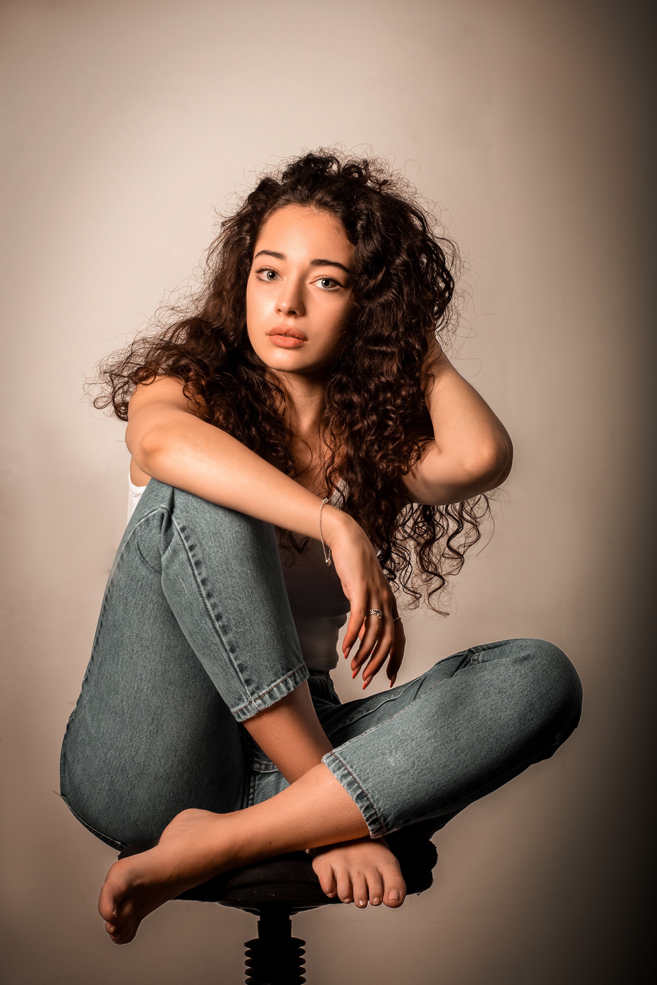 Tess with curly brunette hair sitting in jeans HD Phone Wallpaper