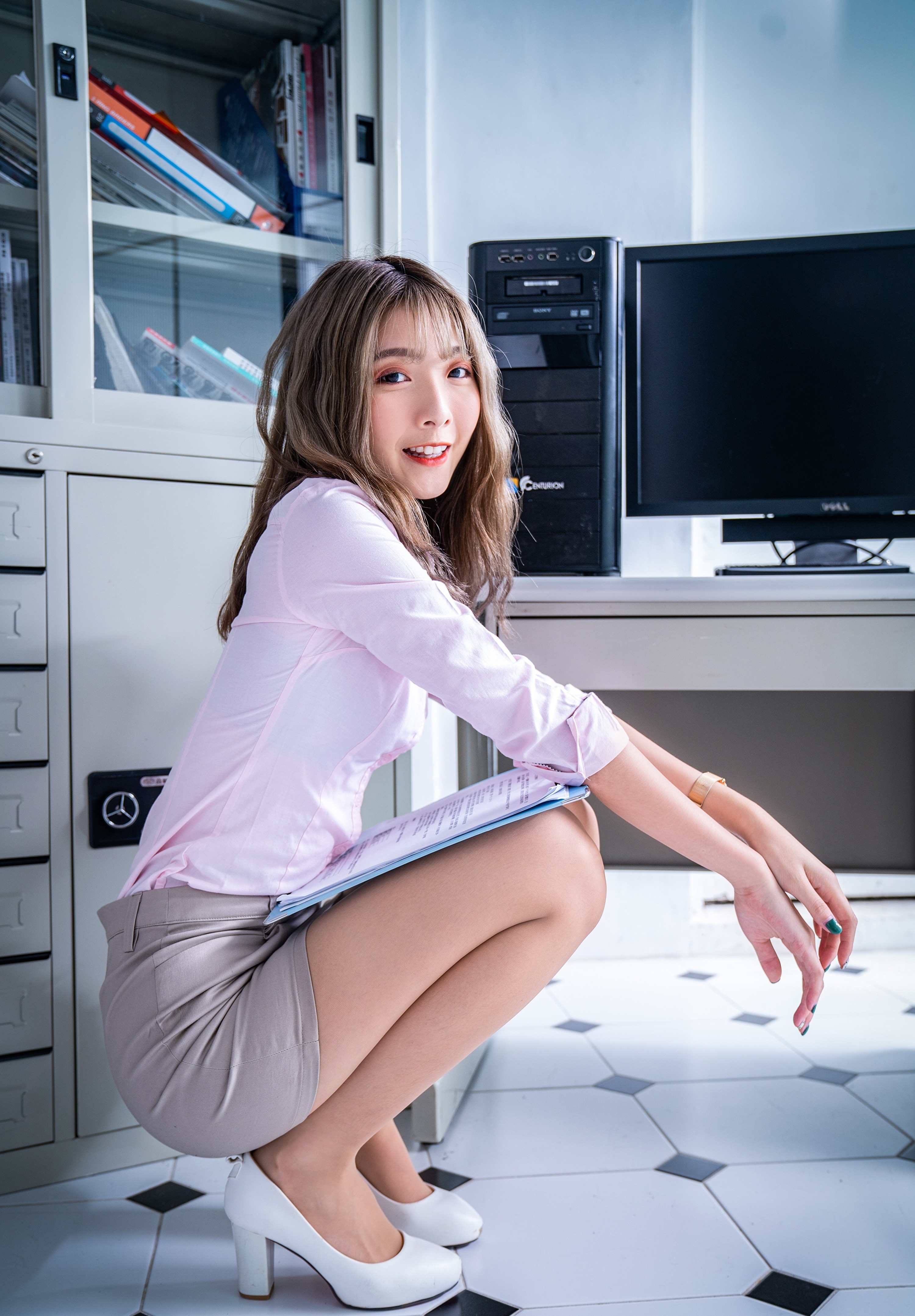 Asian woman in office attire crouching with a clipboard HD Phone Wallpaper