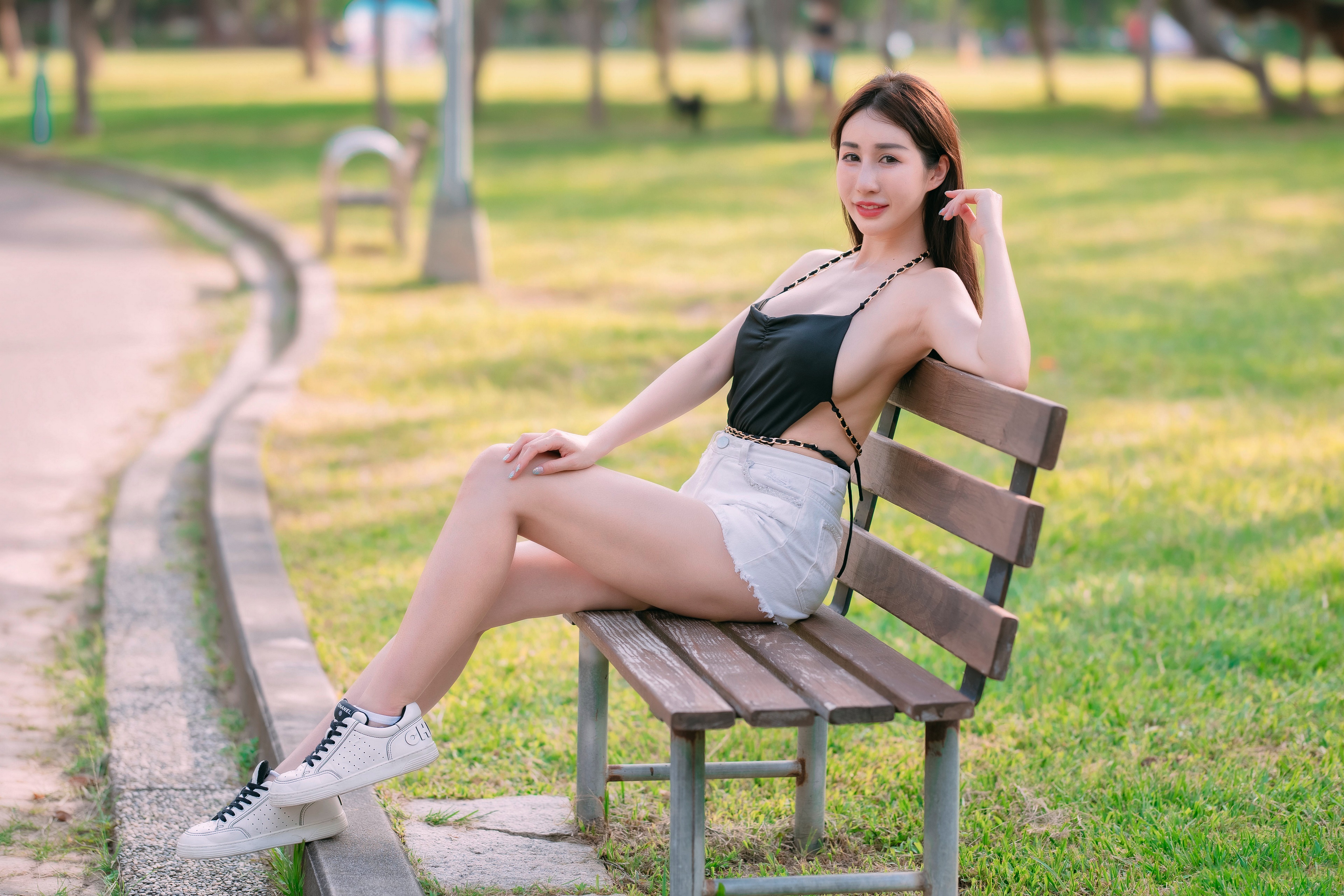 Asian woman in black top and white shorts sitting on a park bench HD Wallpaper