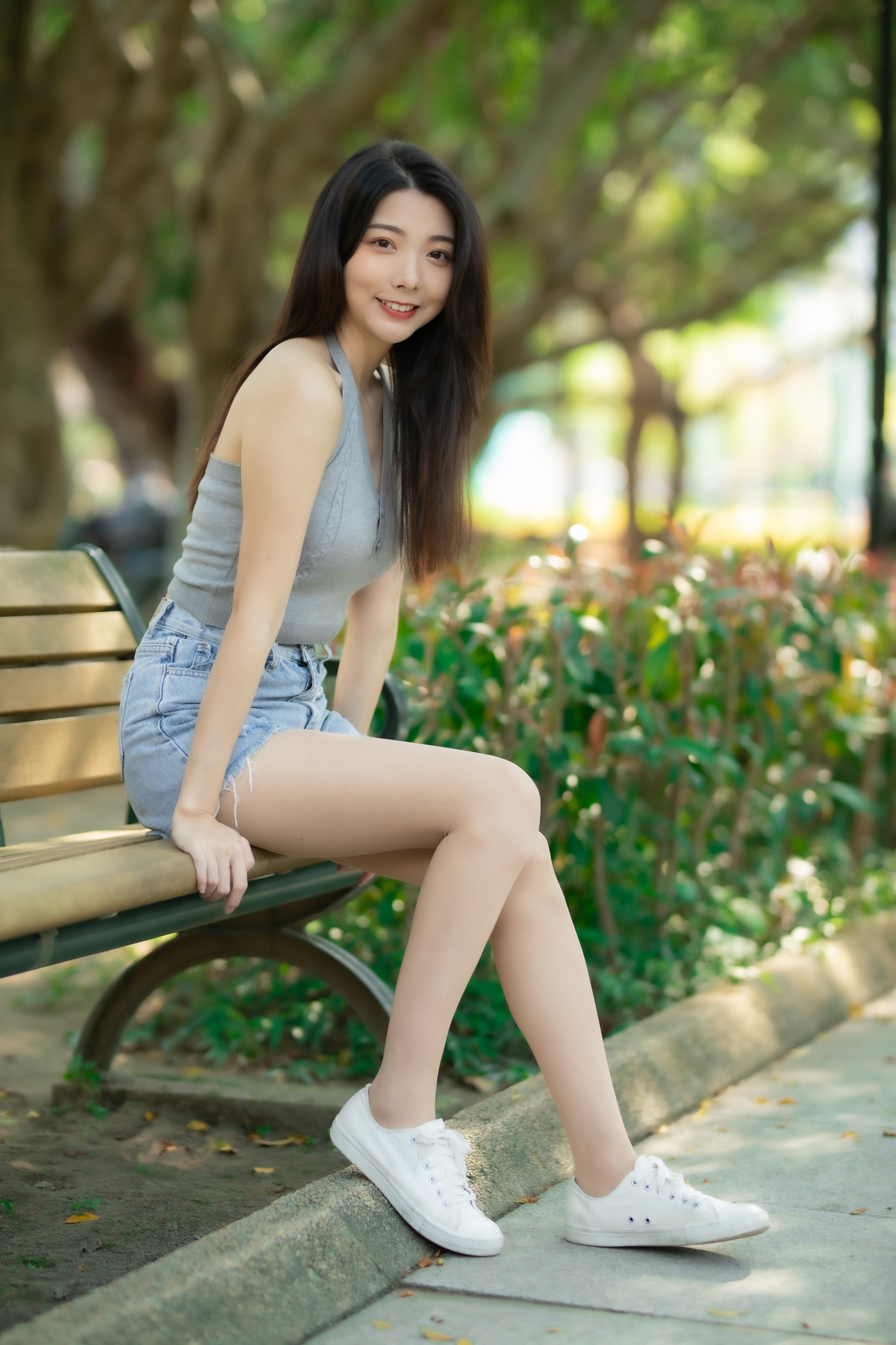 Asian woman sitting on a park bench in shorts and pantyhose HD Phone Wallpaper