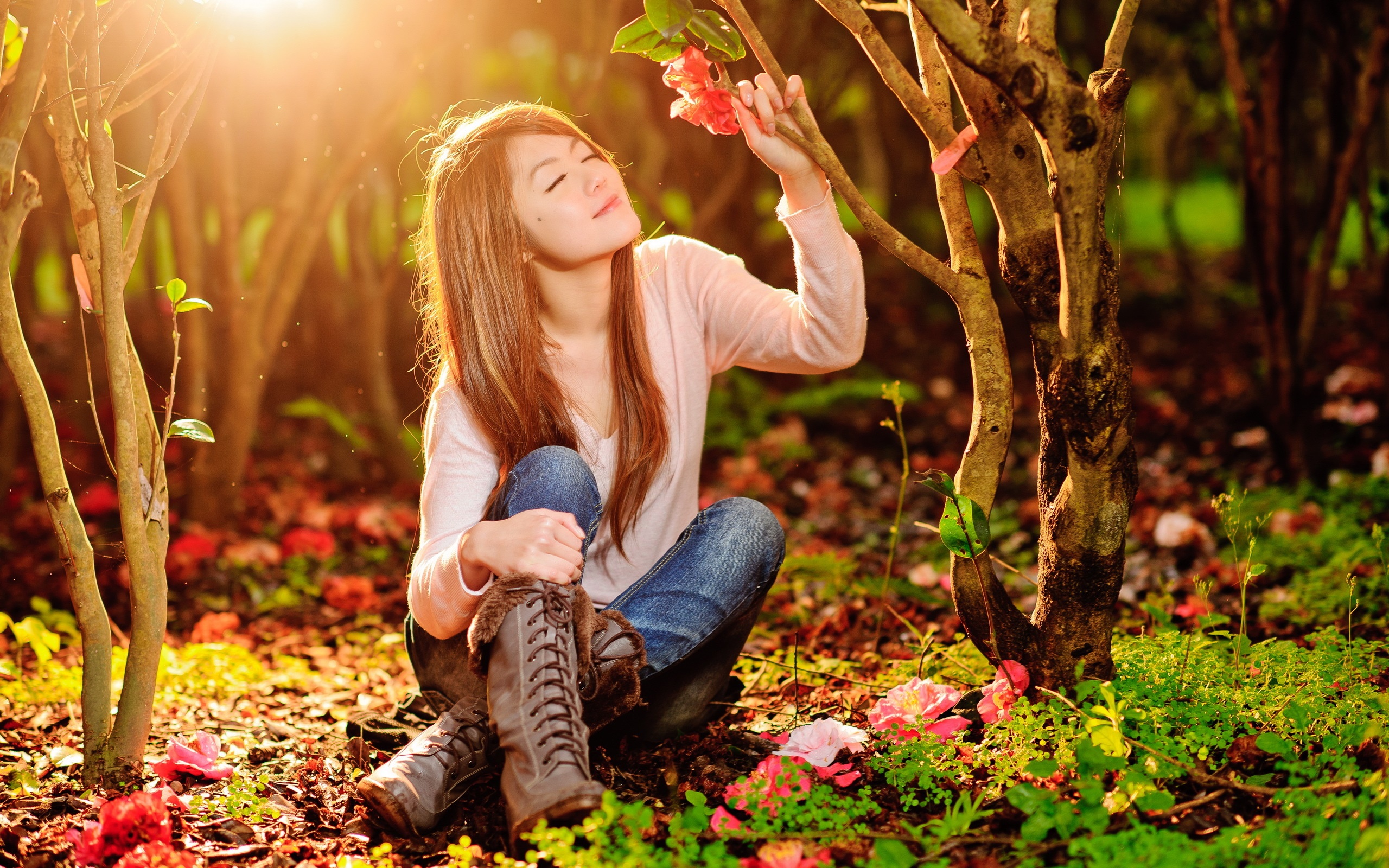 Young woman smelling a flower in a sunlit garden HD Wallpaper