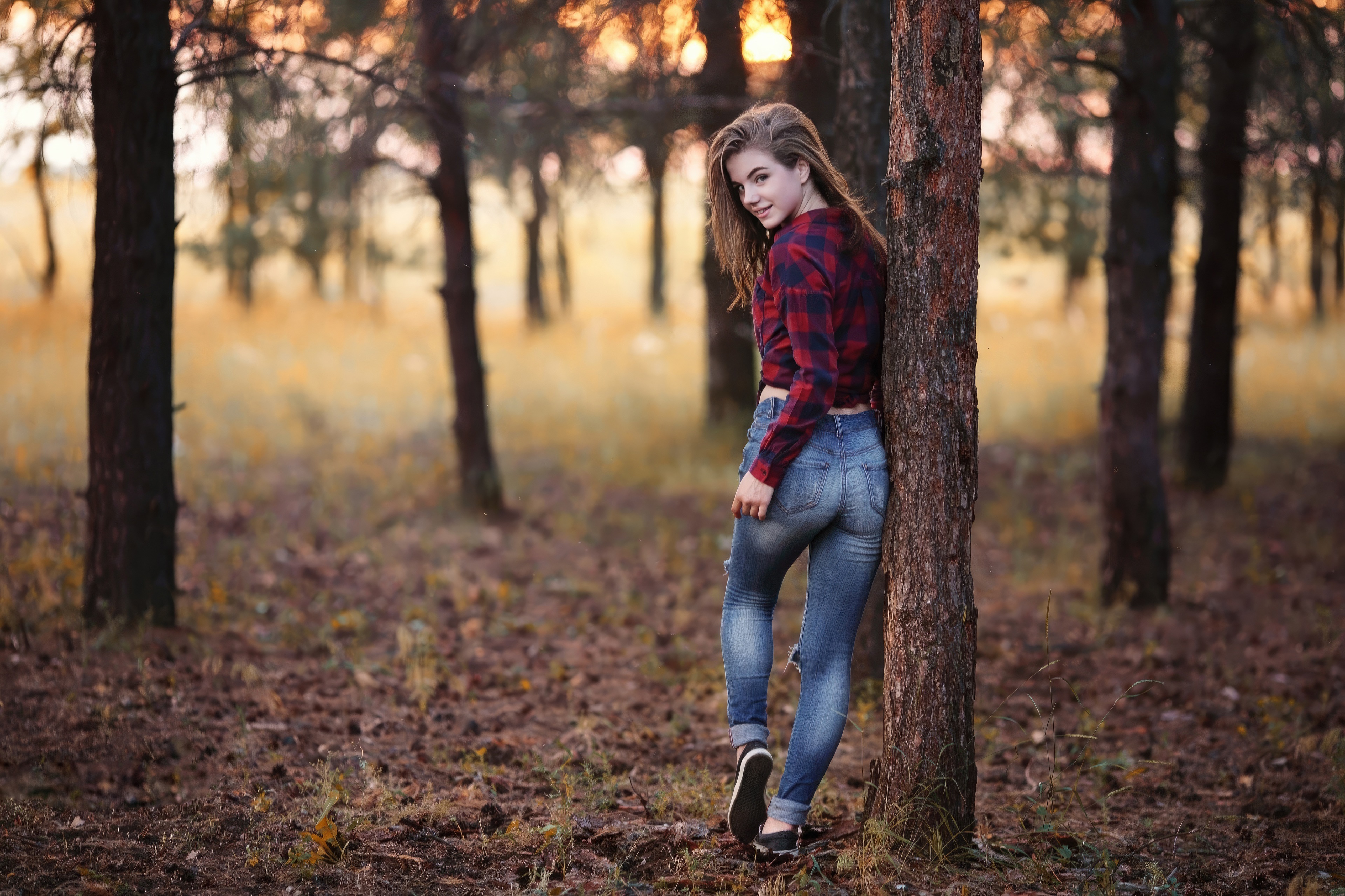 Girl in flannel shirt and jeans leaning on tree HD Wallpaper