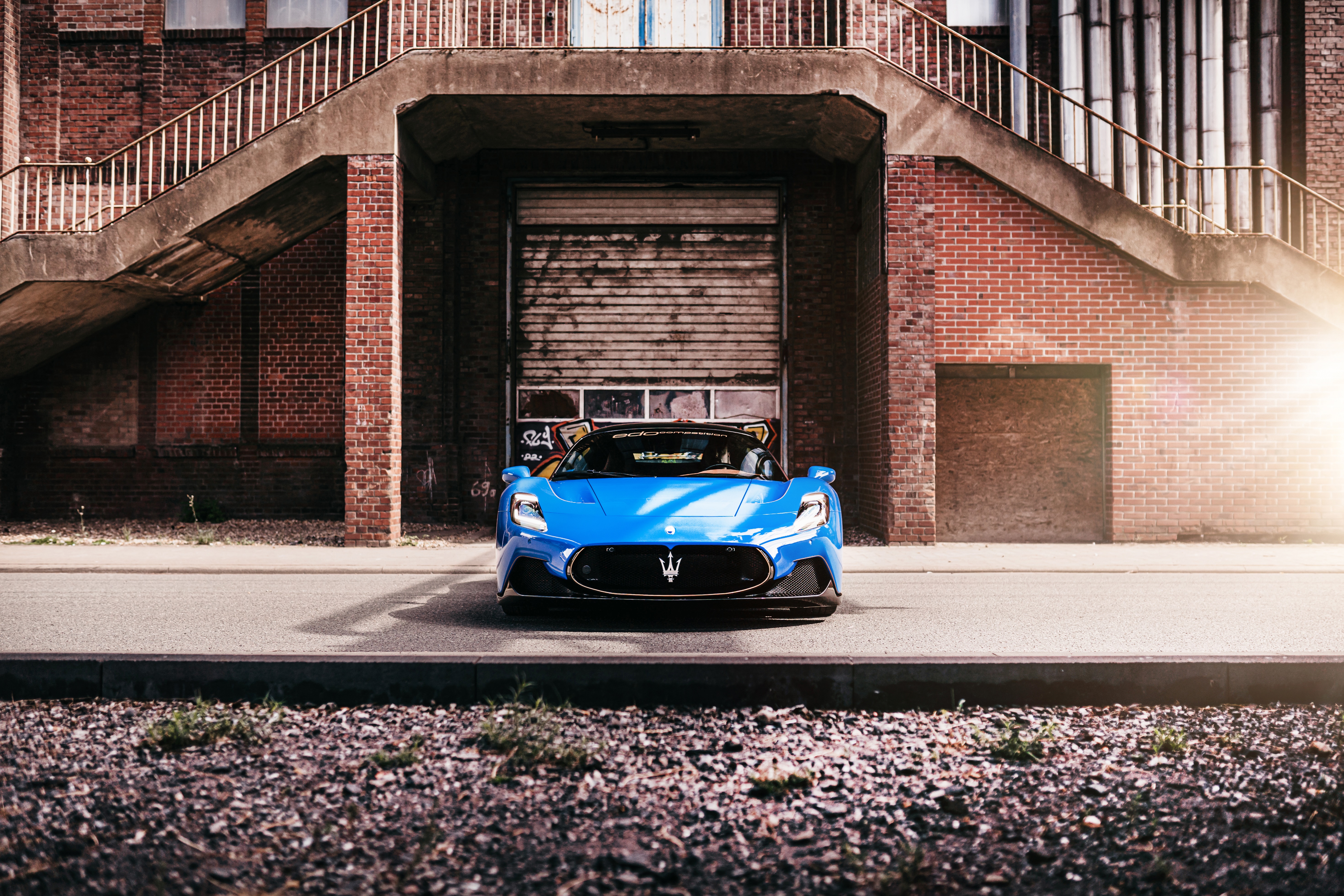 Blue Maserati MC20 in front of brick building HD Wallpaper