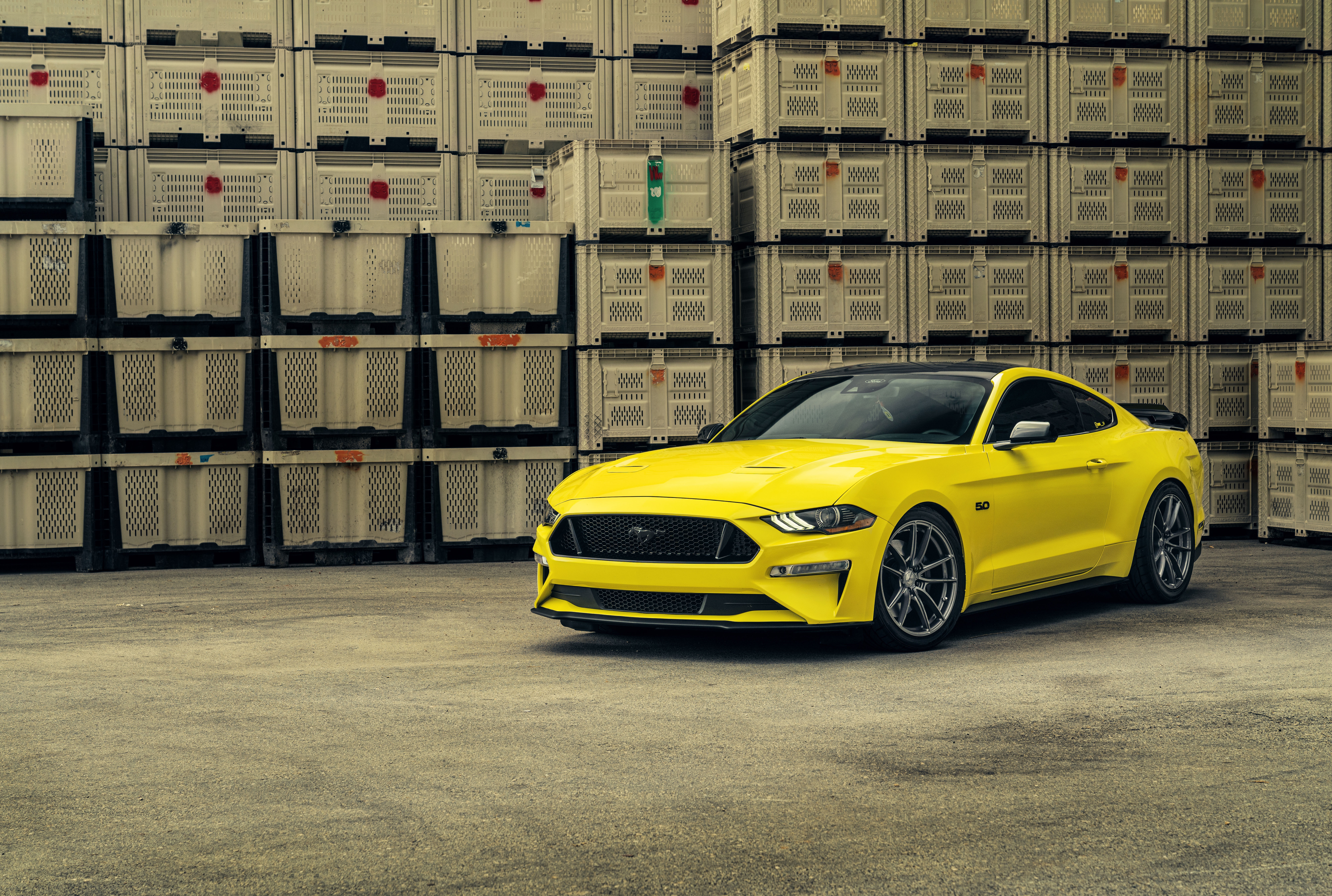 Yellow Ford Mustang parked in front of stacked crates HD Wallpaper