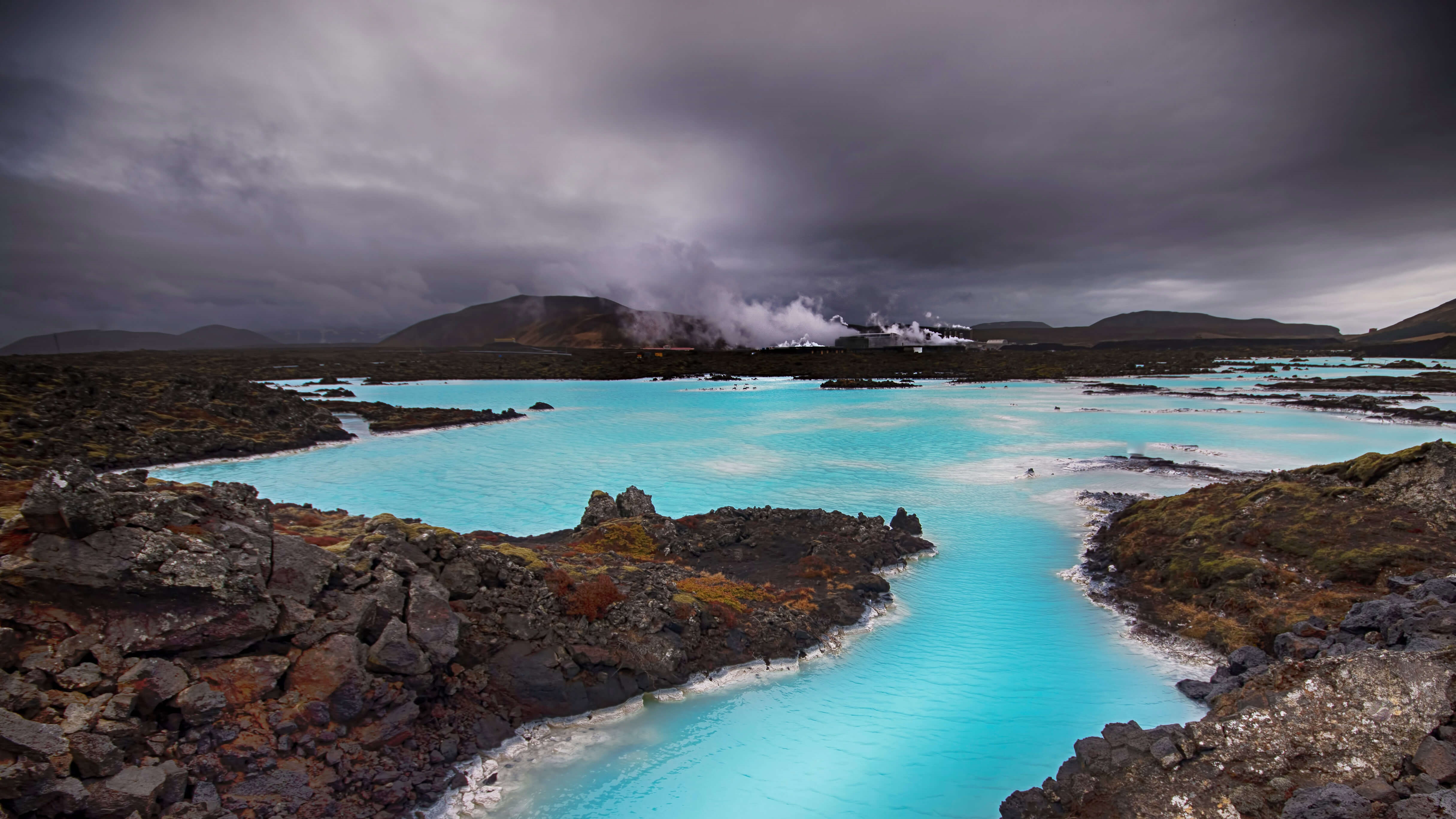 Blue Lagoon geothermal spa with steam and dark clouds HD Wallpaper