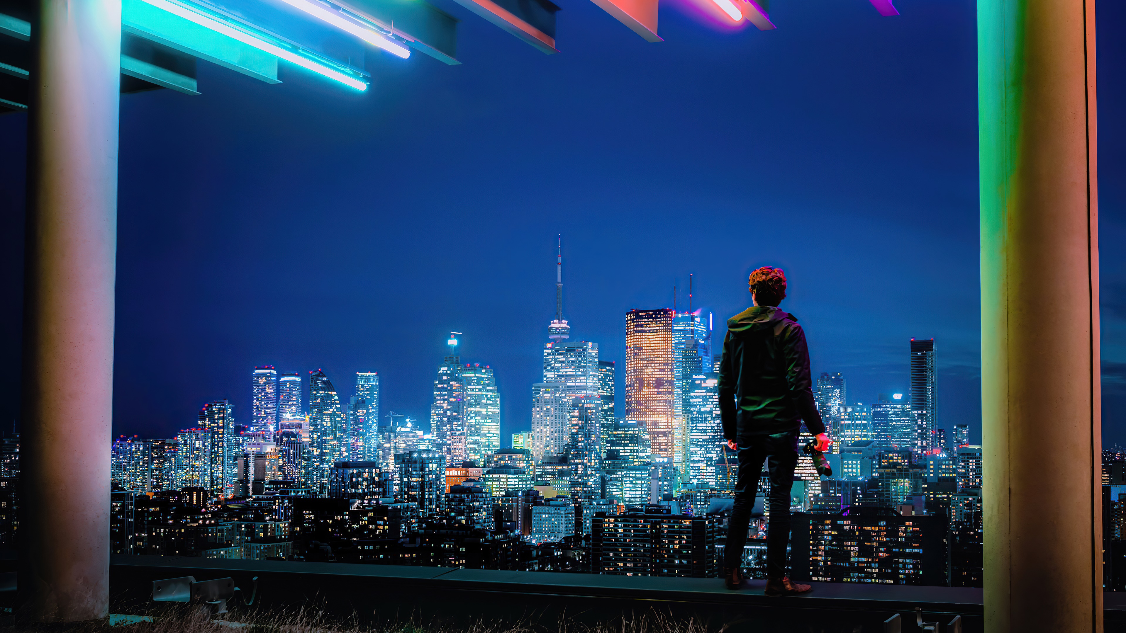 Man with camera overlooking city skyline at night HD Wallpaper