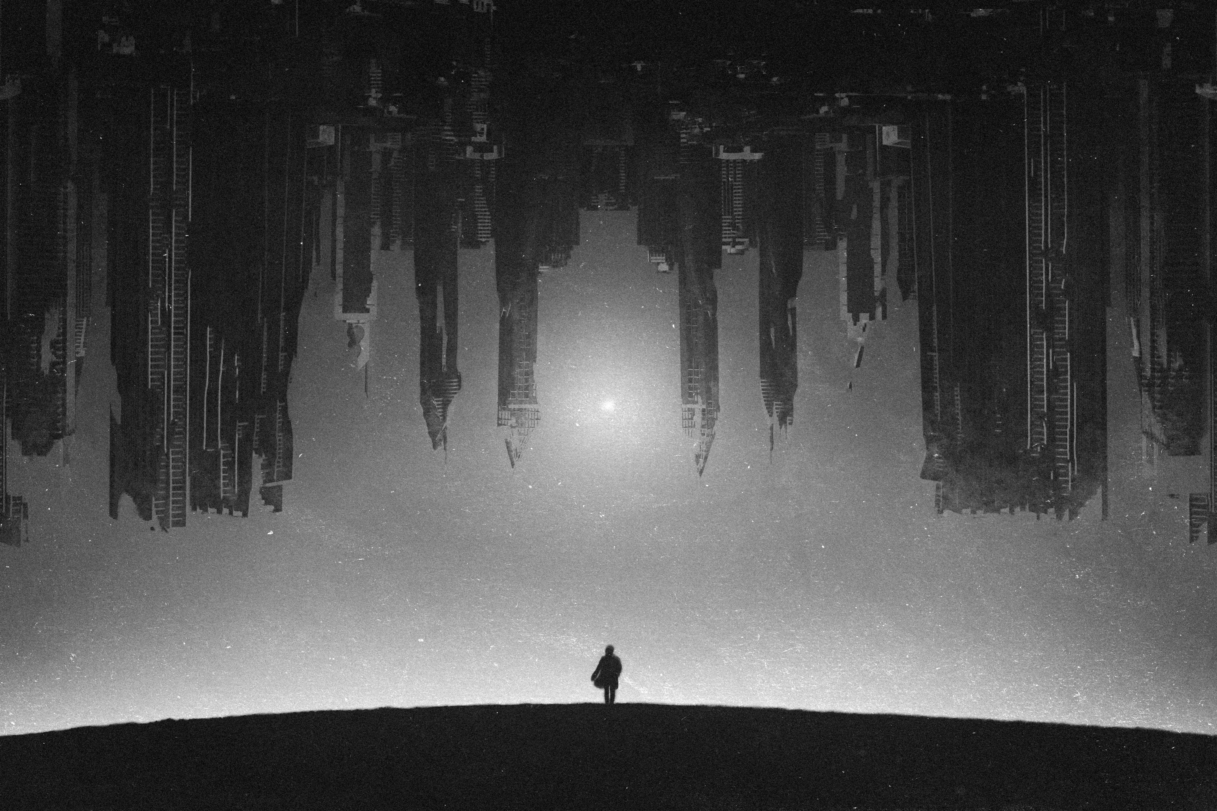 Monochrome artwork of a person facing an inverted cityscape HD Wallpaper