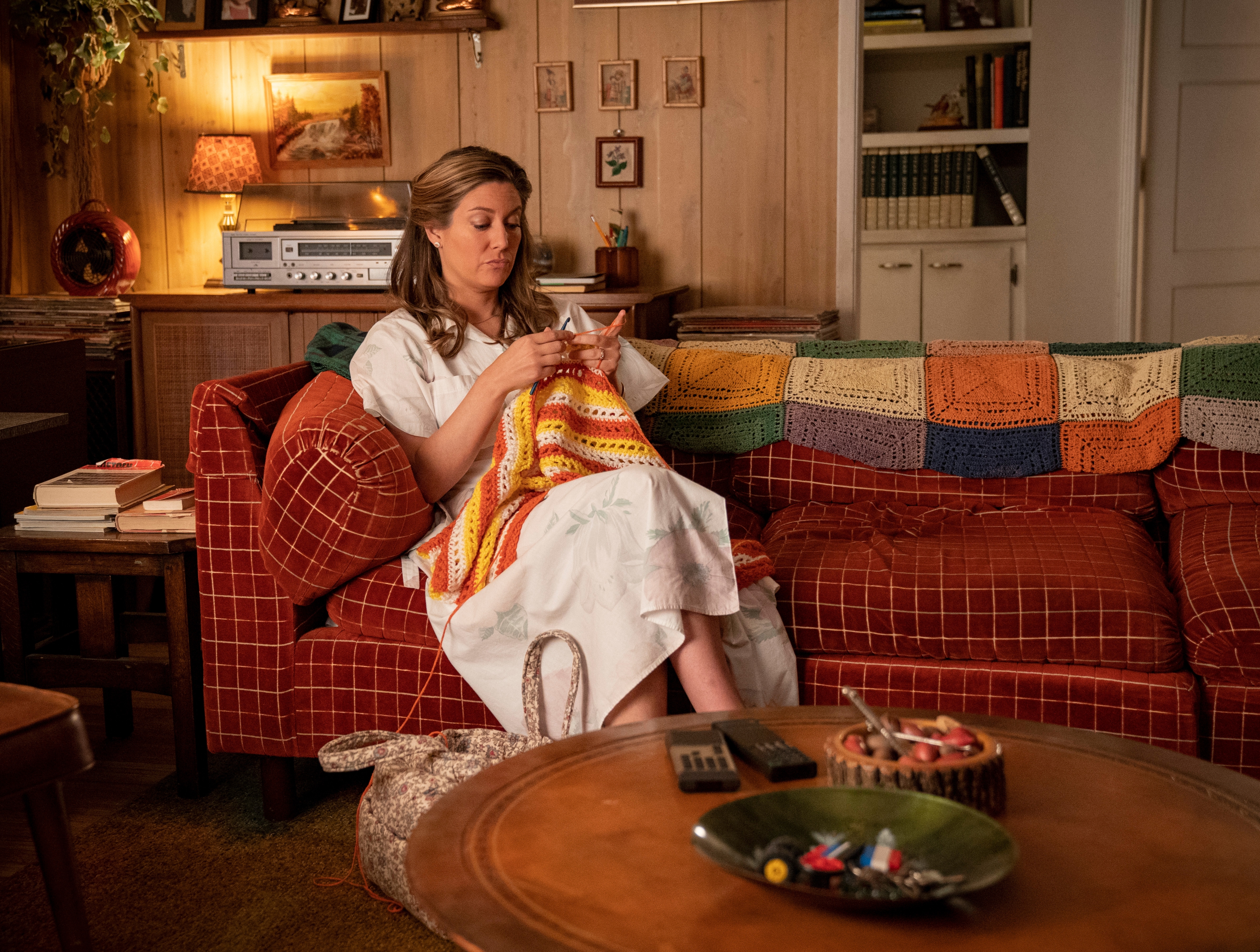 Mary Cooper knitting a colorful blanket on a plaid couch HD Wallpaper