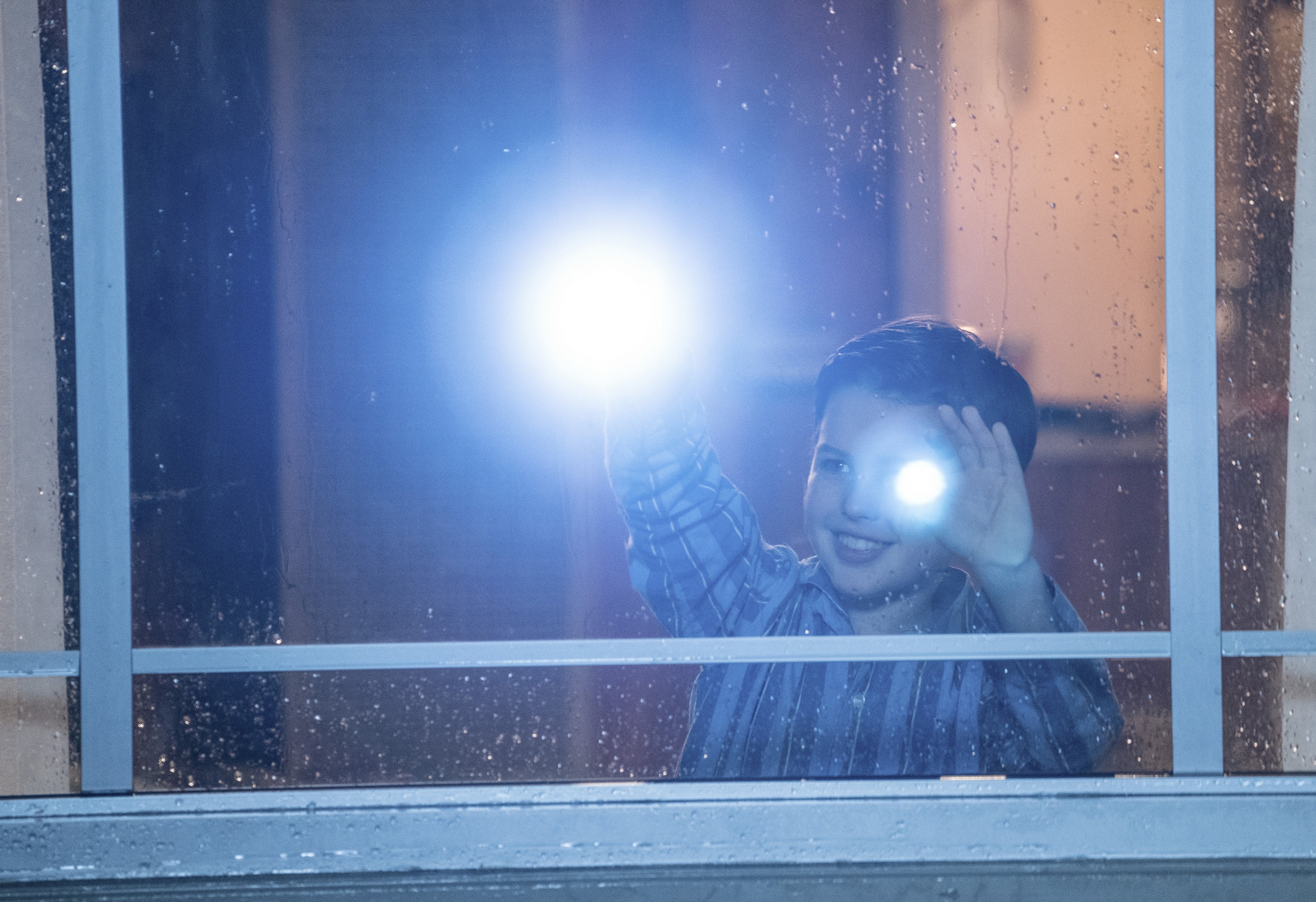Young Sheldon with a flashlight through a wet window HD Wallpaper