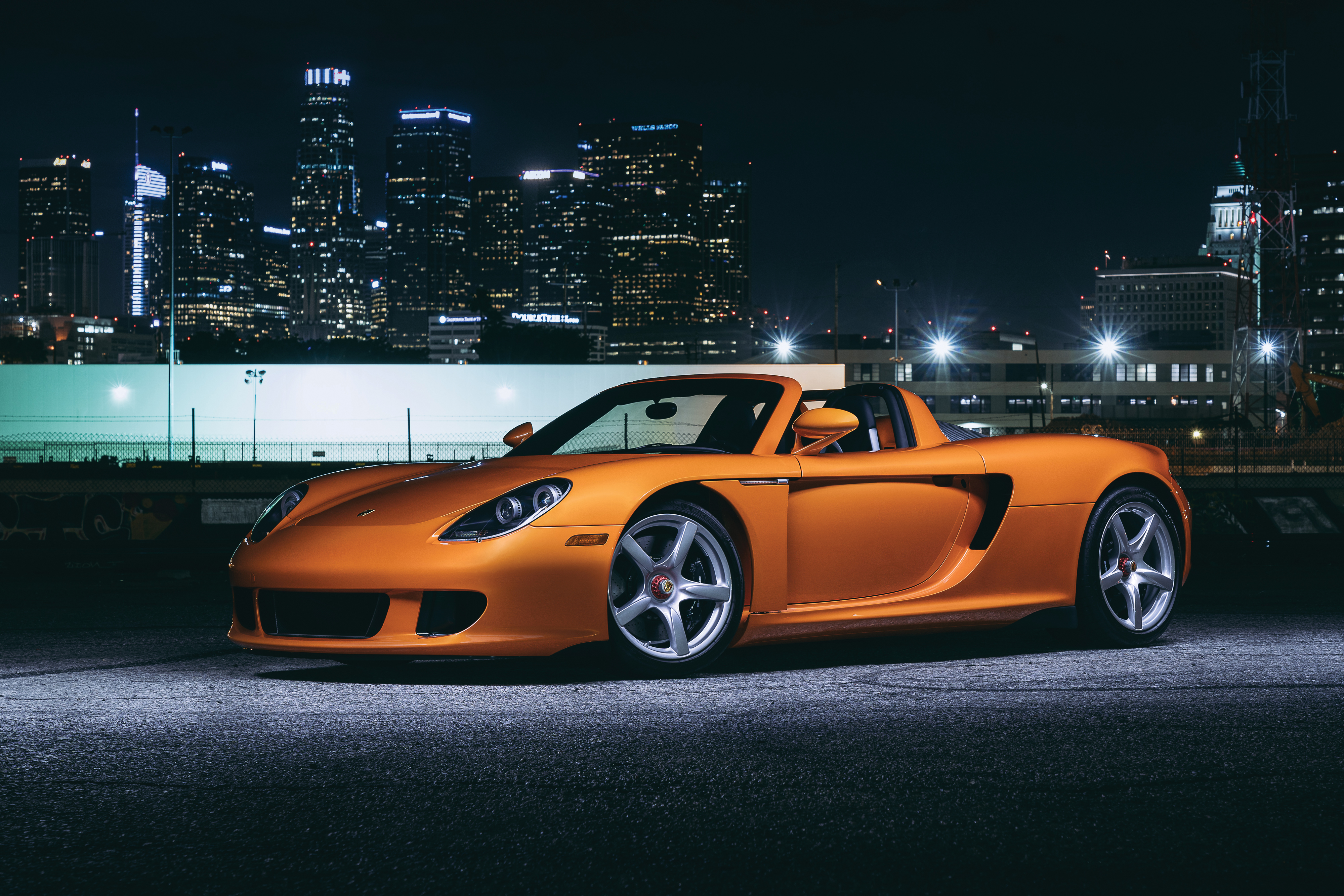 Orange Porsche Carrera GT at night with city skyline 4K HD Wallpaper
