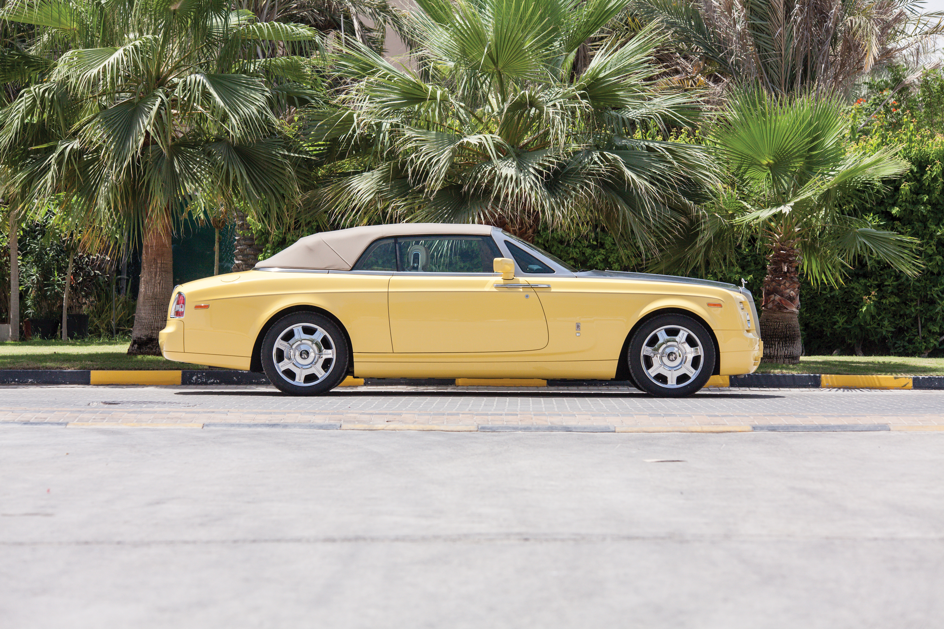Yellow Rolls-Royce Phantom convertible parked among palm trees HD Wallpaper
