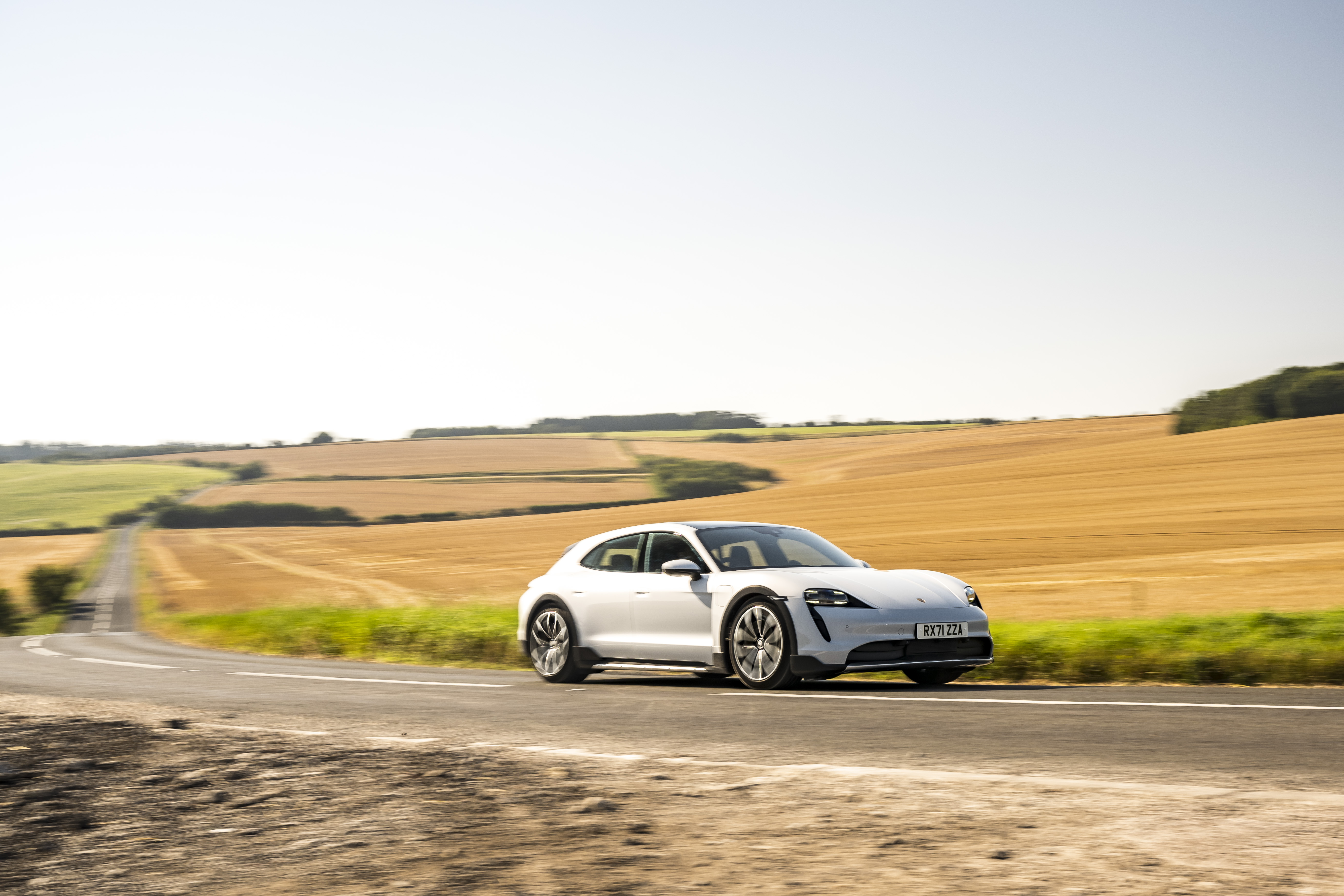 White Porsche Taycan 4S driving through golden fields HD Wallpaper