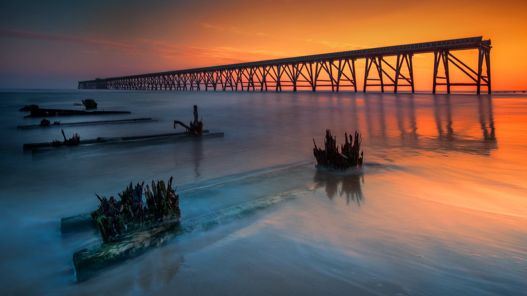 Orange sunset over pier and calm ocean HD Wallpaper