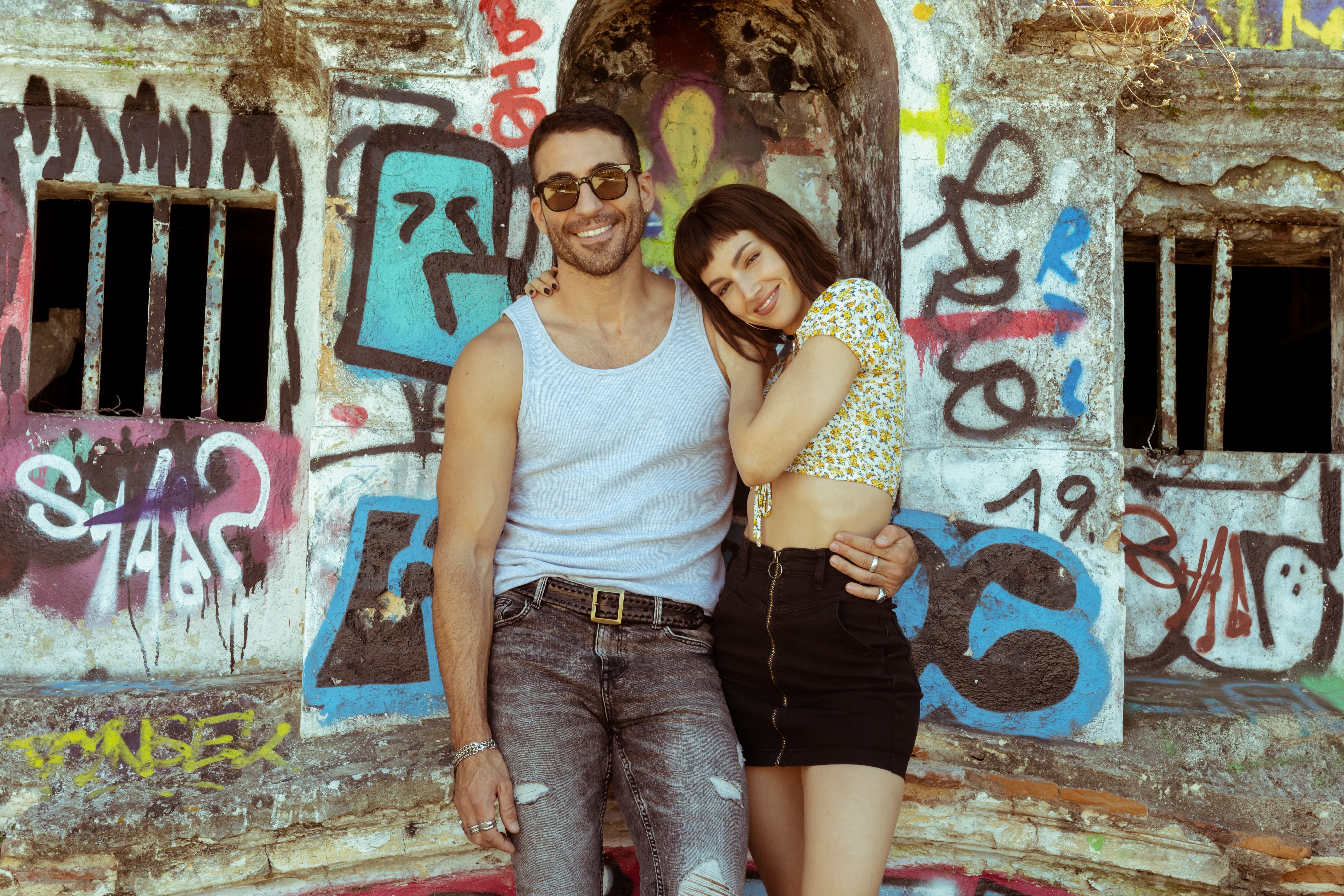 Úrsula Corberó and Miguel Herrán smiling by graffiti wall HD Wallpaper