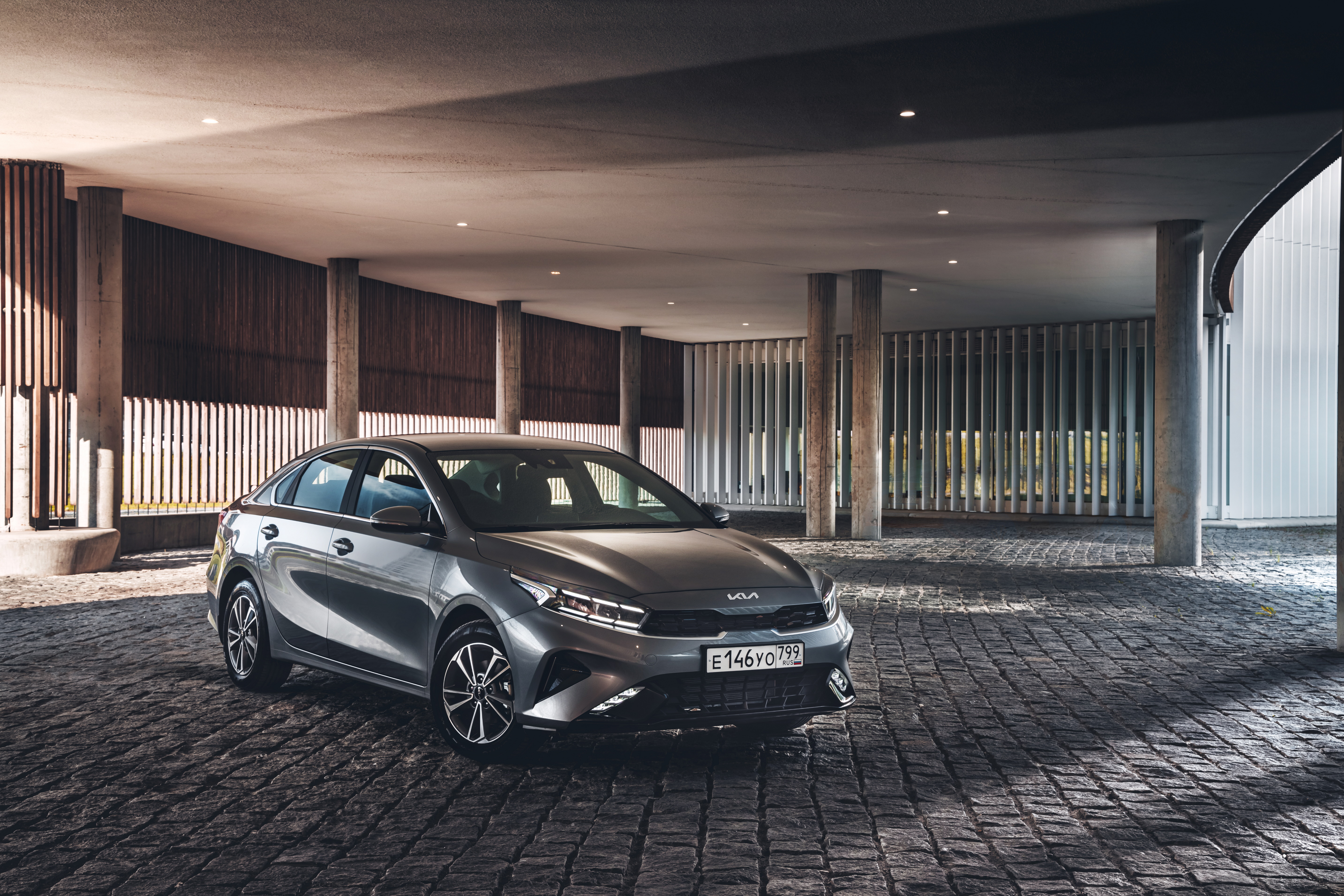 Grey Kia Cerato parked under modern architecture HD Wallpaper