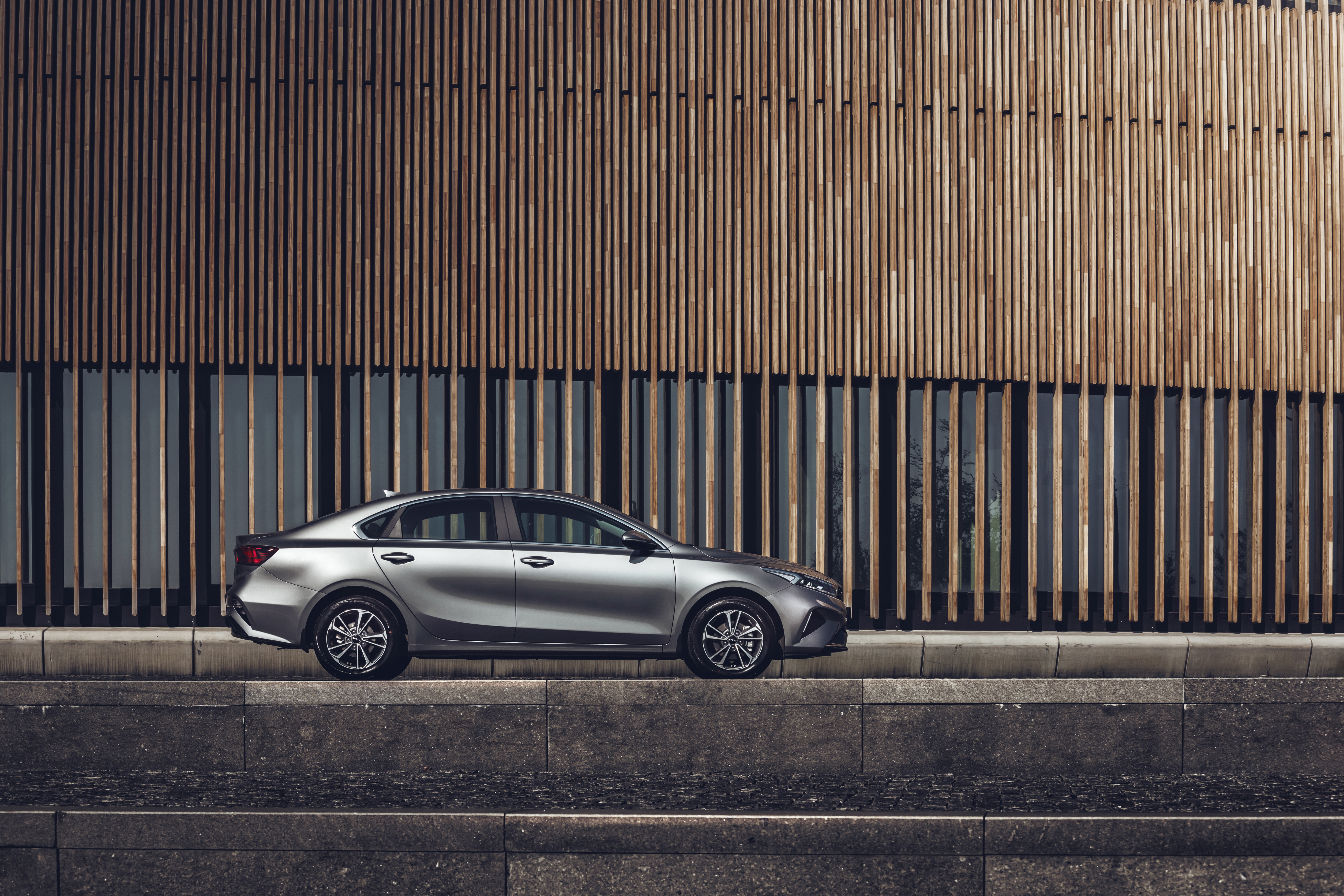 Silver Kia Cerato parked against modern wooden building HD Wallpaper