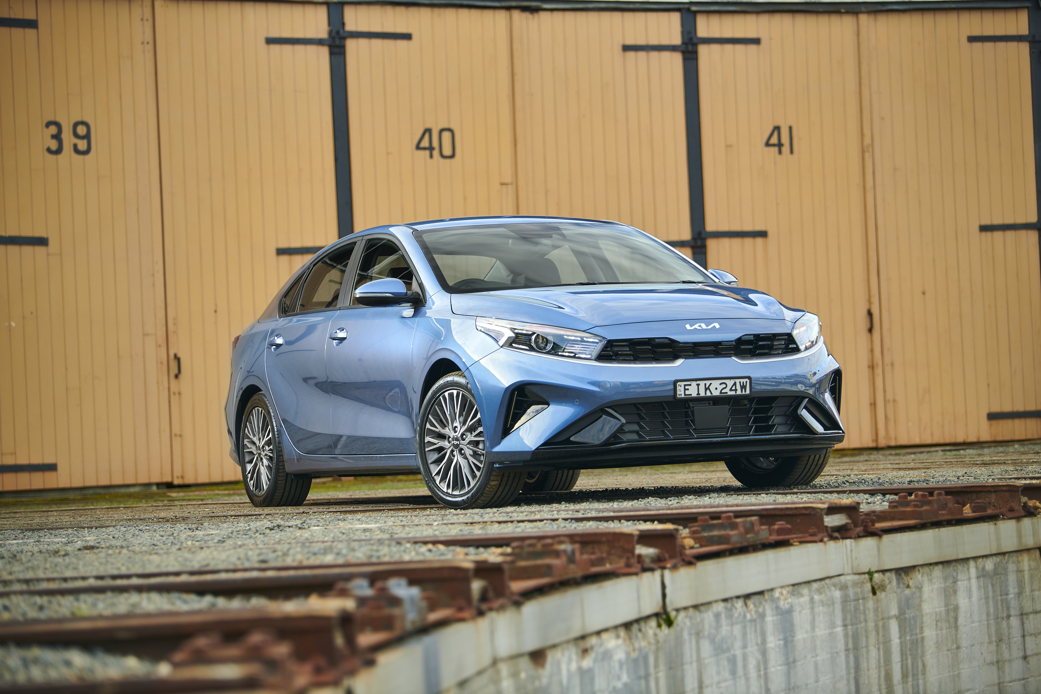 Blue Kia Cerato Sport Plus parked by numbered garages HD Wallpaper