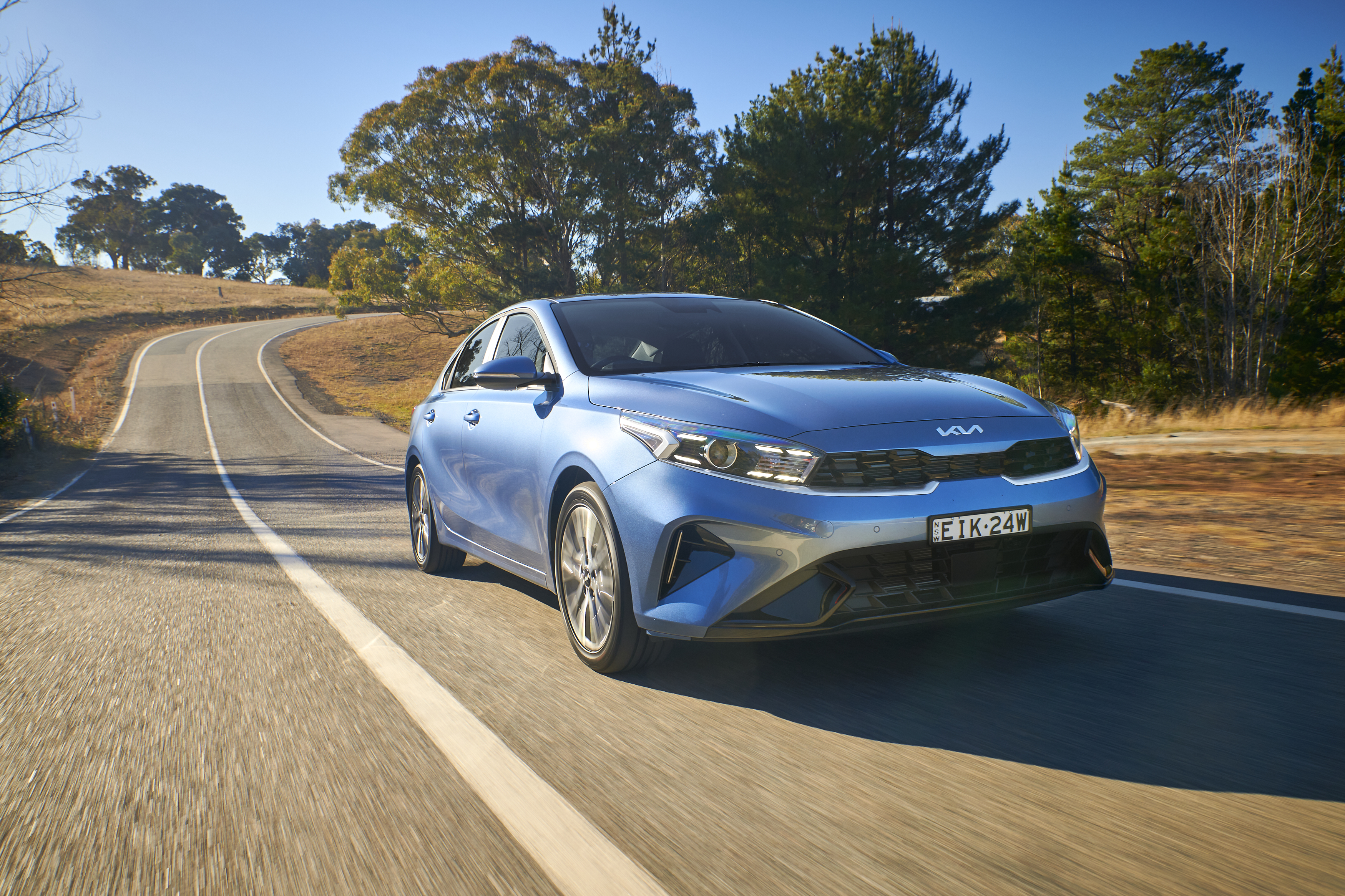Blue Kia Cerato Sport Plus compact car on a winding road HD Wallpaper