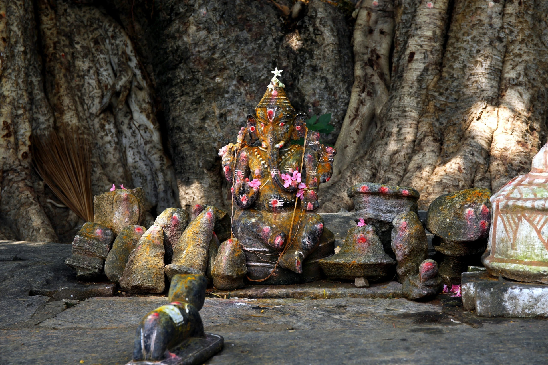 Hindu Ganesh statue adorned with flowers under a tree HD Wallpaper