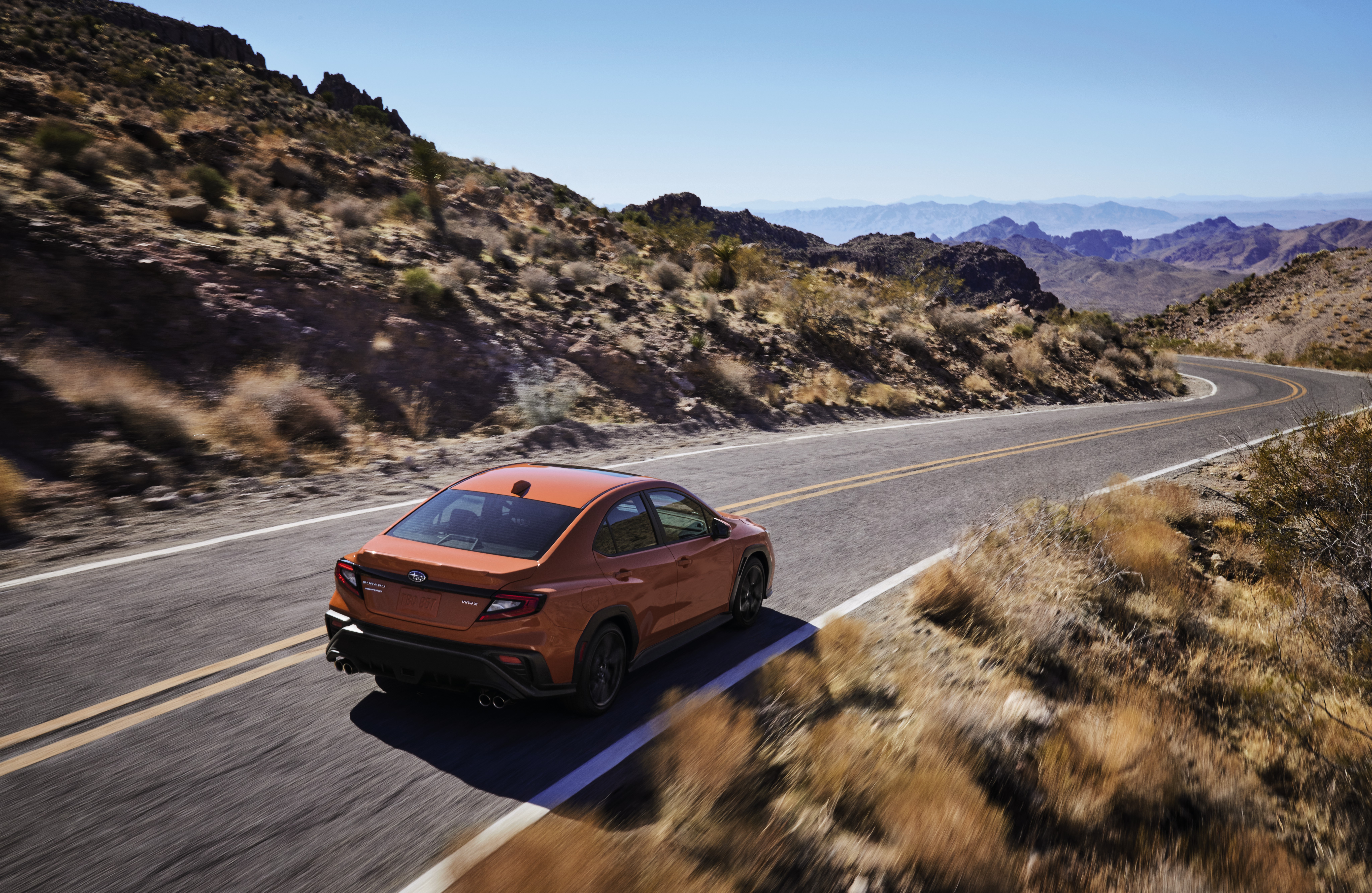Orange Subaru WRX sport car on a winding desert road HD Wallpaper