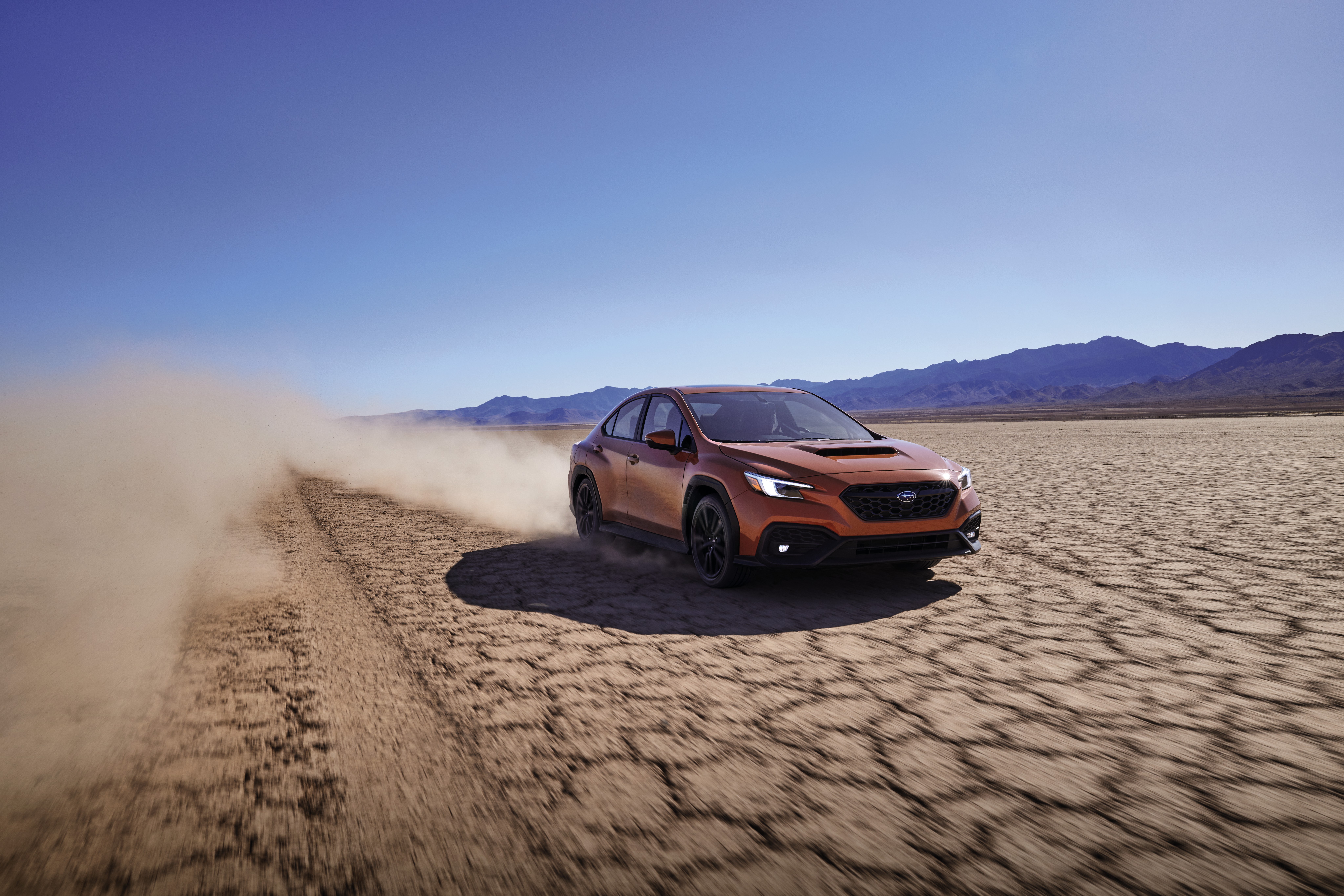 Orange Subaru WRX sport car kicking up dust in desert HD Wallpaper