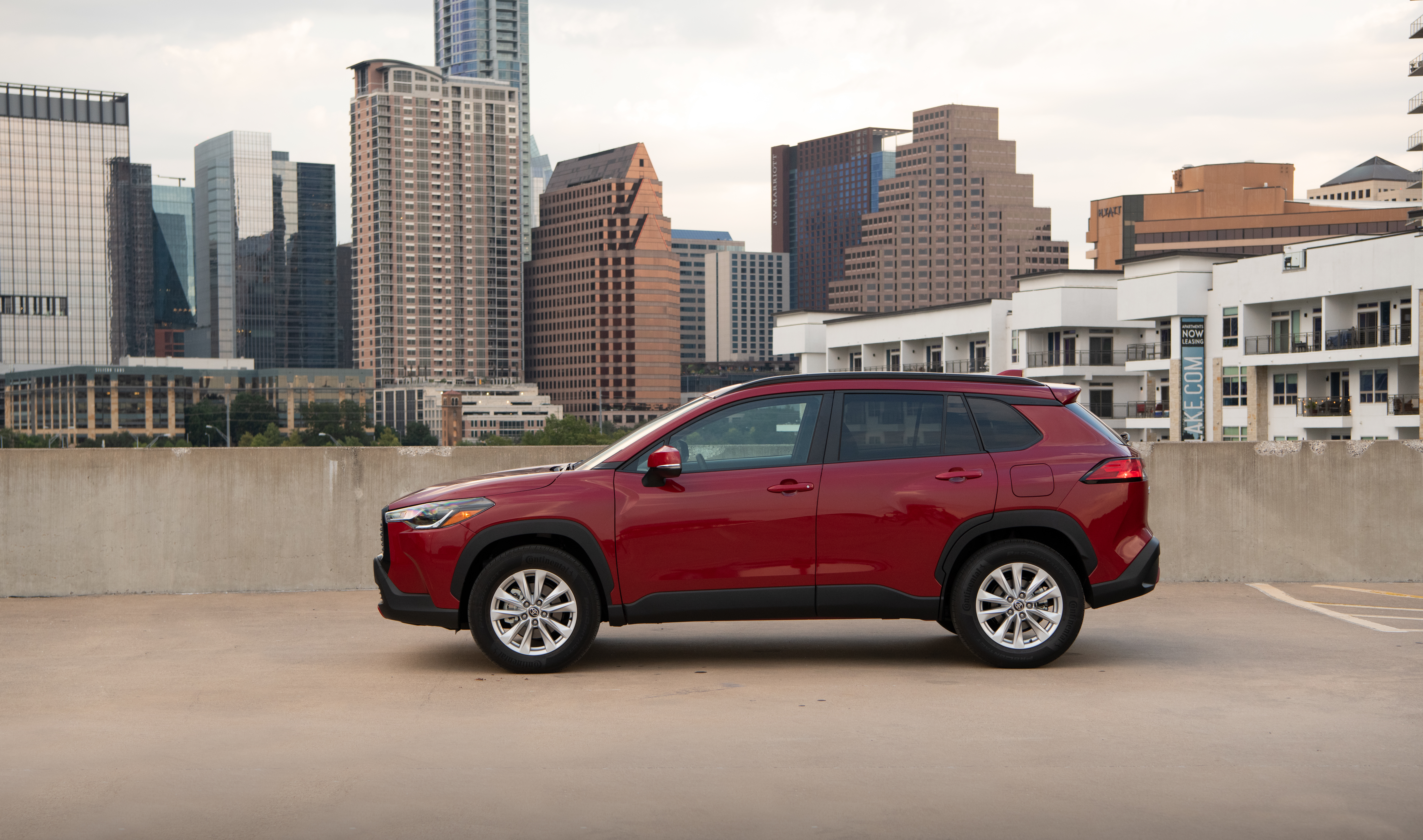 Red Toyota Corolla Cross SUV with city skyline HD Wallpaper
